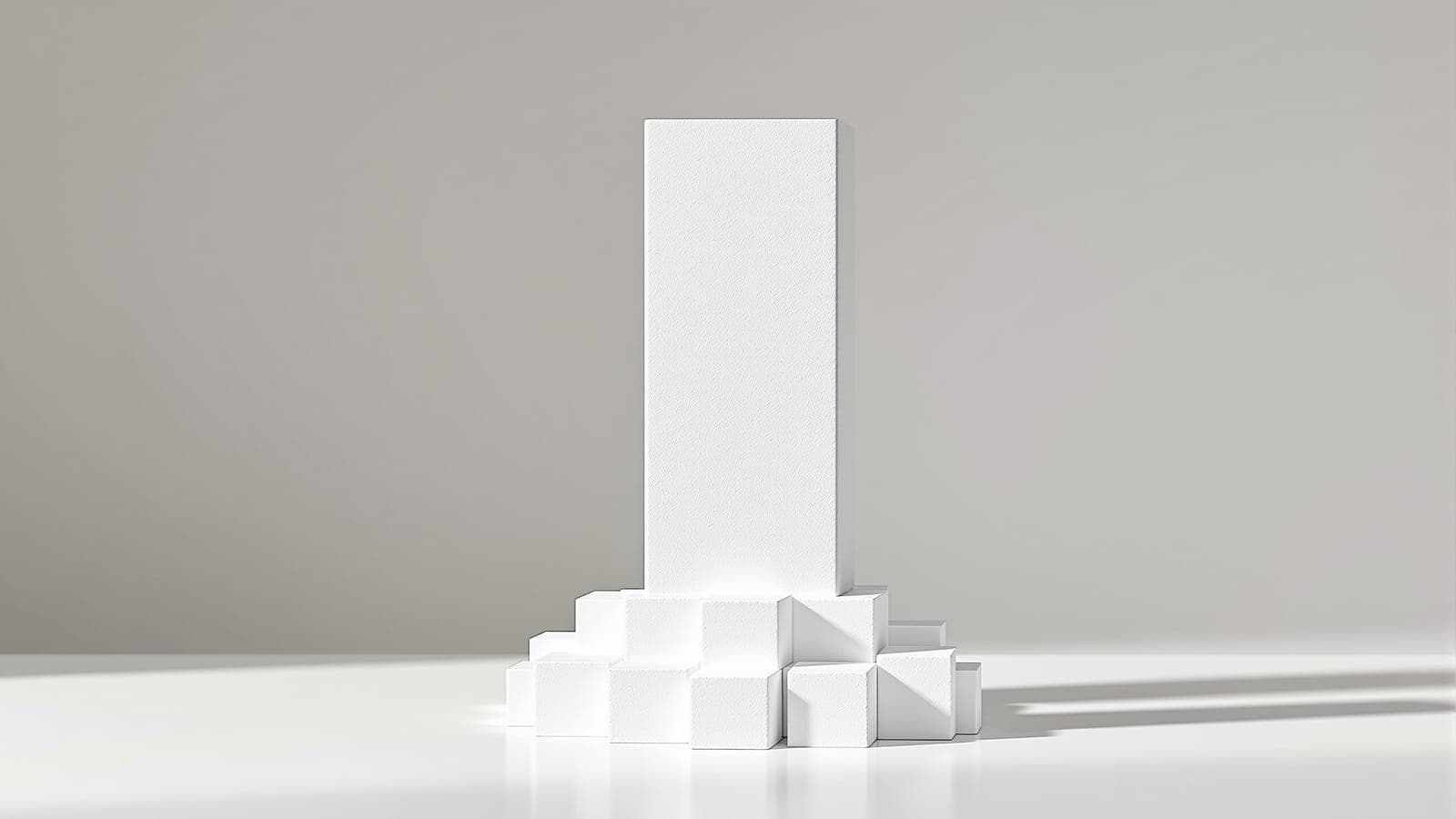 A tall foam block standing over a low cluster of smaller blocks on a plain base, one form clearly dominant