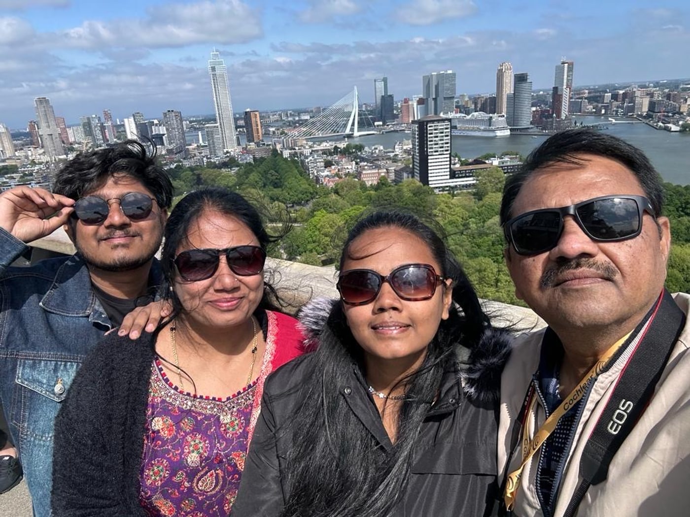 Amogh with his family at a high viewpoint over Rotterdam, the Erasmus Bridge and the city skyline on the Nieuwe Maas spread out behind them