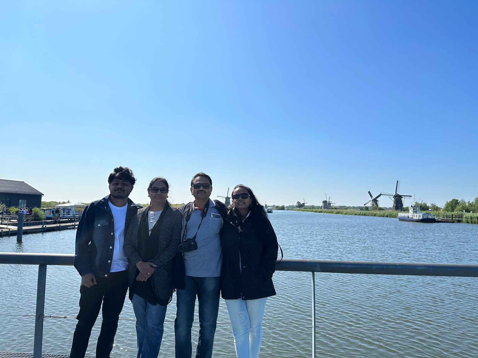 Amogh with his family beside the canal at Kinderdijk, the drainage windmills of the polder standing across the water behind them