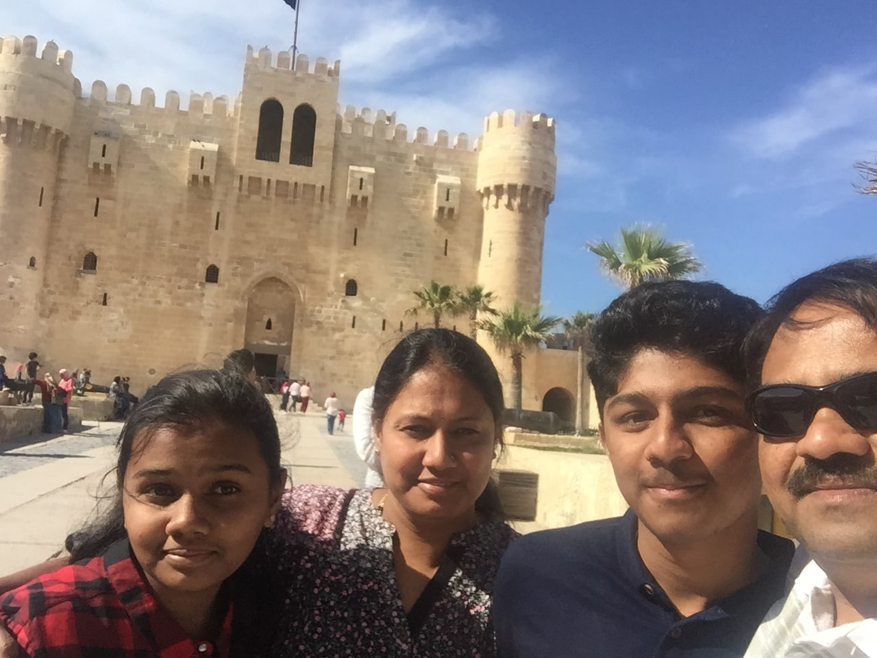 Amogh with his sister, mother and father in front of the Fort of Qaitbay in Alexandria, the honey-coloured crenellated fortress built on the site of the ancient Lighthouse of Alexandria from its own fallen stones, under a bright blue sky