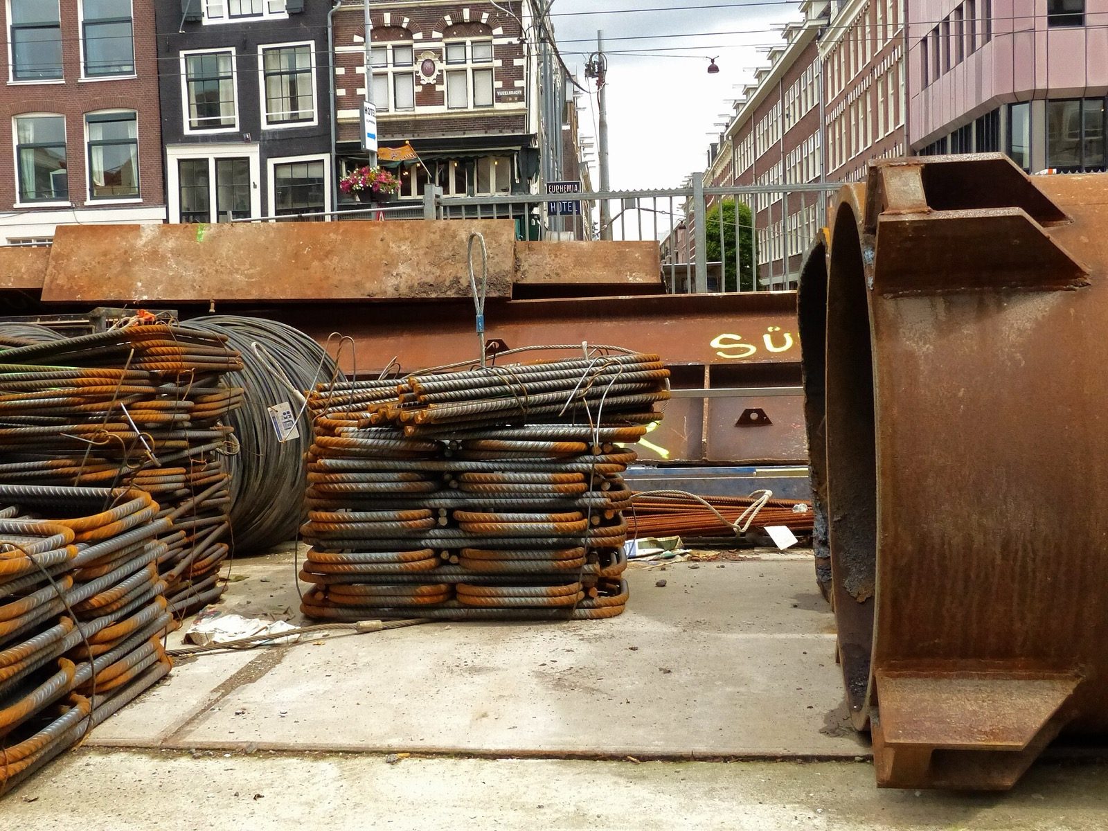 Bundles of ribbed steel reinforcement bars of different diameters stacked and tied on a construction site, ready to be cut and bent — the raw material that a bar bending schedule quantifies and orders by weight