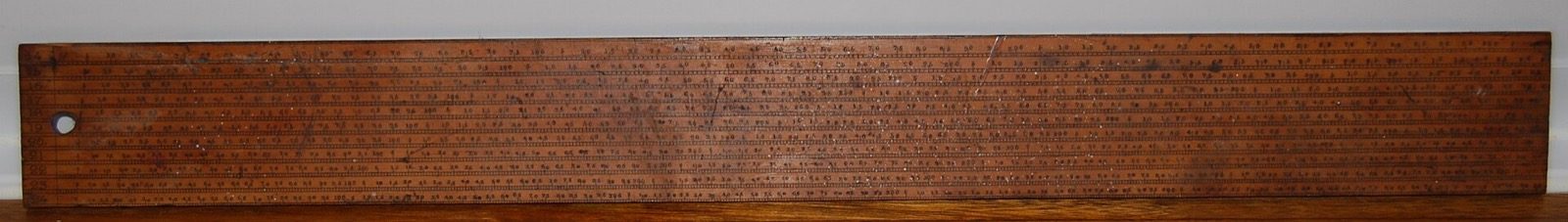A long flat wooden draughtsman's scale rule covered with many fine engraved measuring scales running its full length