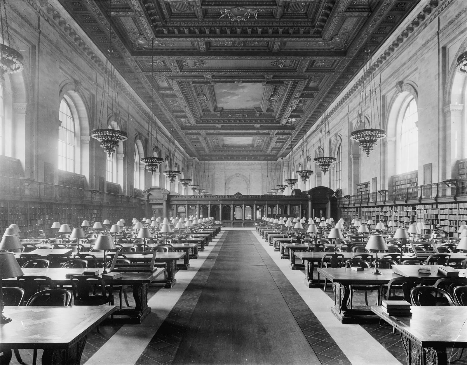 Furniture defining a monumental public room — the long tables, chairs and lamps of the New York Public Library's Rose Reading Room organise the whole vast space.