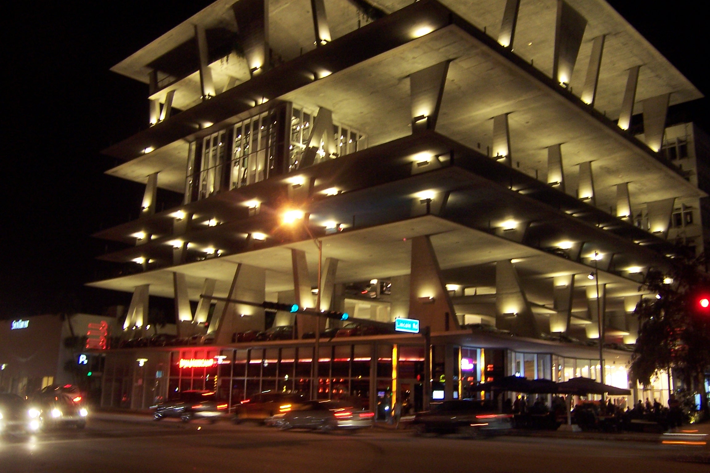 Exterior of the open concrete garage illuminated at night, showing the stacked unequal floor plates.