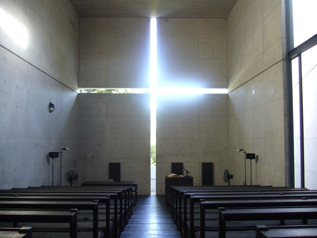 Interior of the Church of the Light showing the cruciform slit of daylight behind the altar and the timber bench pews.