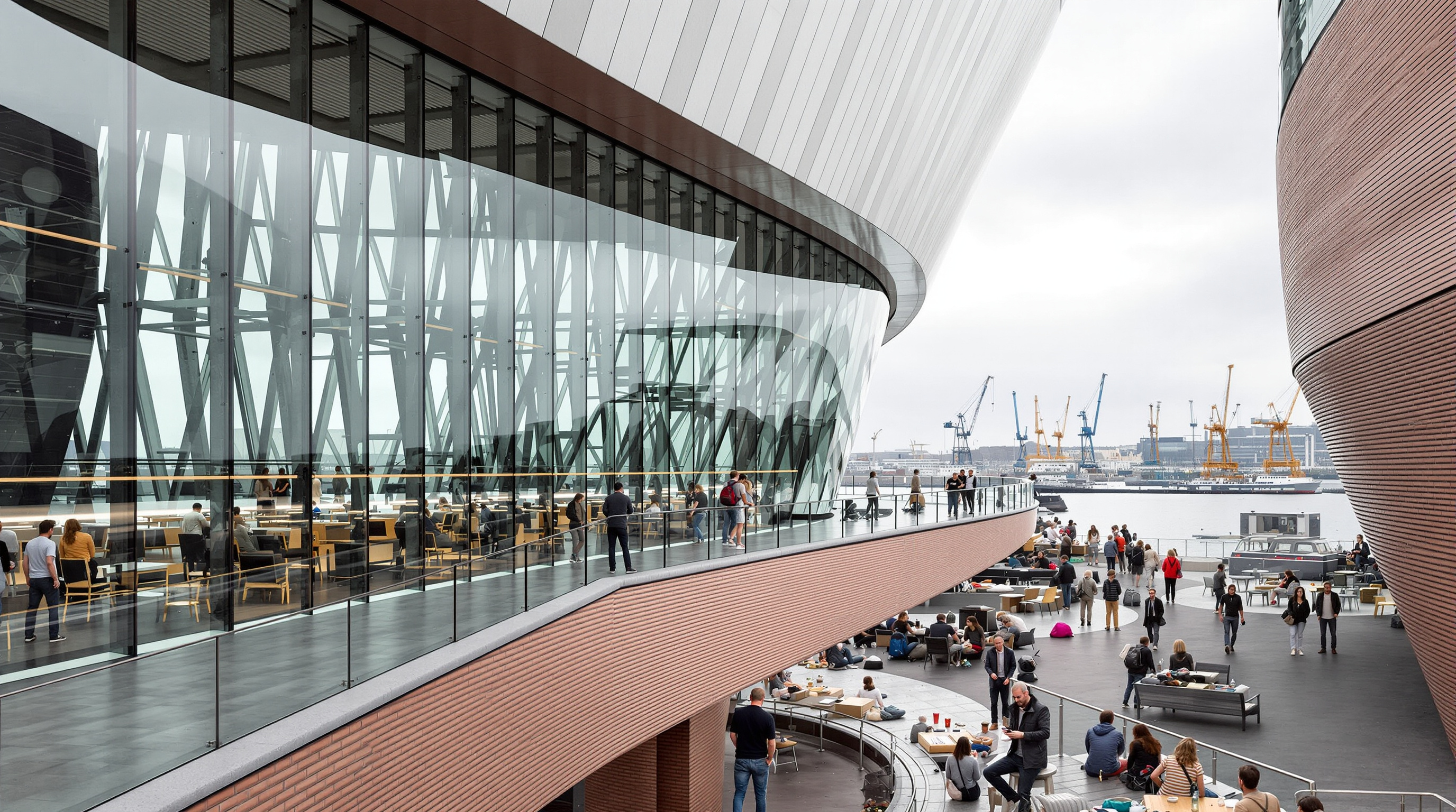 Visitors standing on the open-air Plaza terrace of the Elbphilharmonie at the seam between brick and glass, looking out over Hamburg harbour, the curved wall of the glass superstructure rising behind them