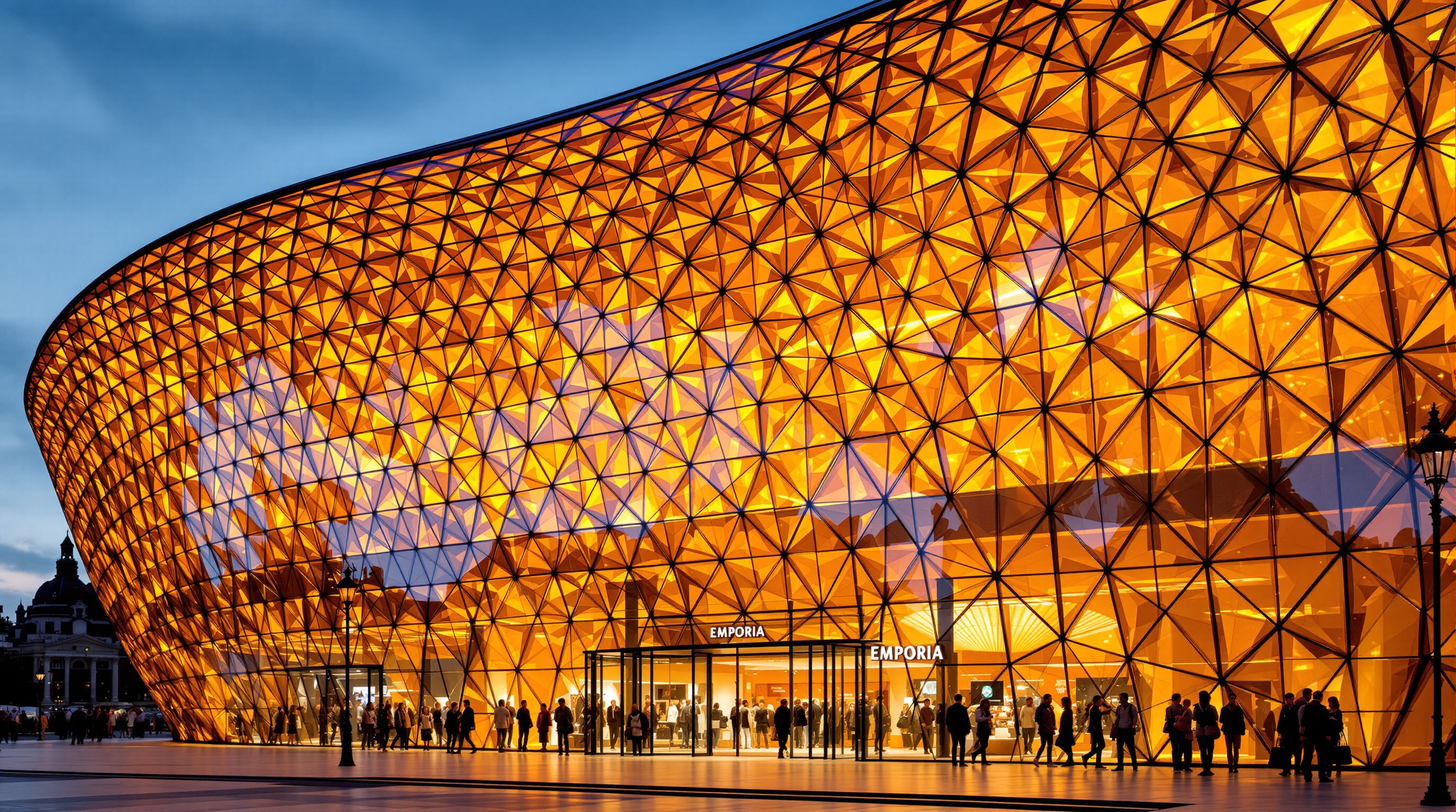 The molten amber glass entrance of Emporia seen up close at dusk, the curved gridshell of golden panels glowing from within like honey, casting warm light across shoppers entering beneath the inward-curling lip of glass