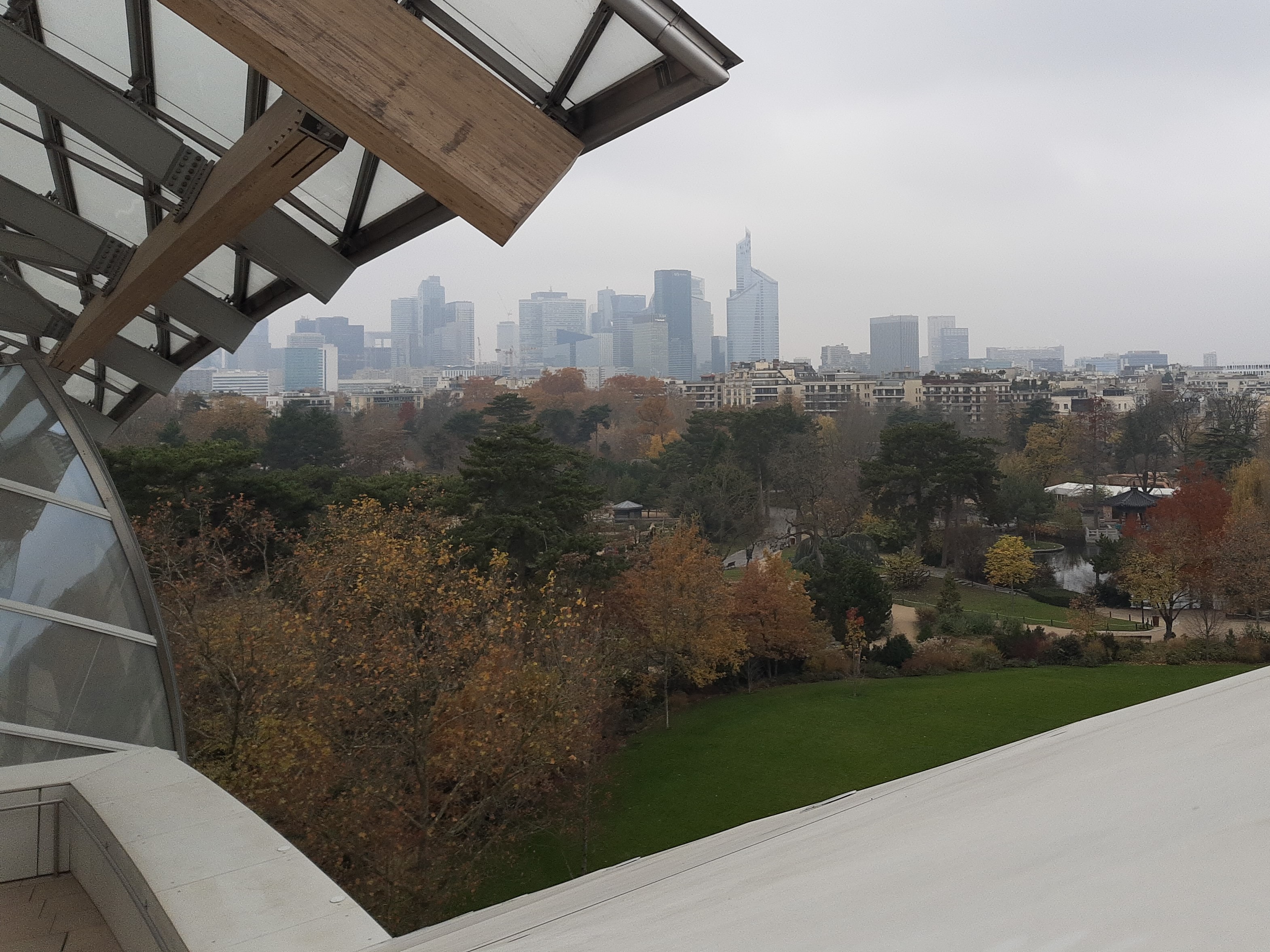 The Fondation's glass sails with the towers of La Défense visible in the distance.