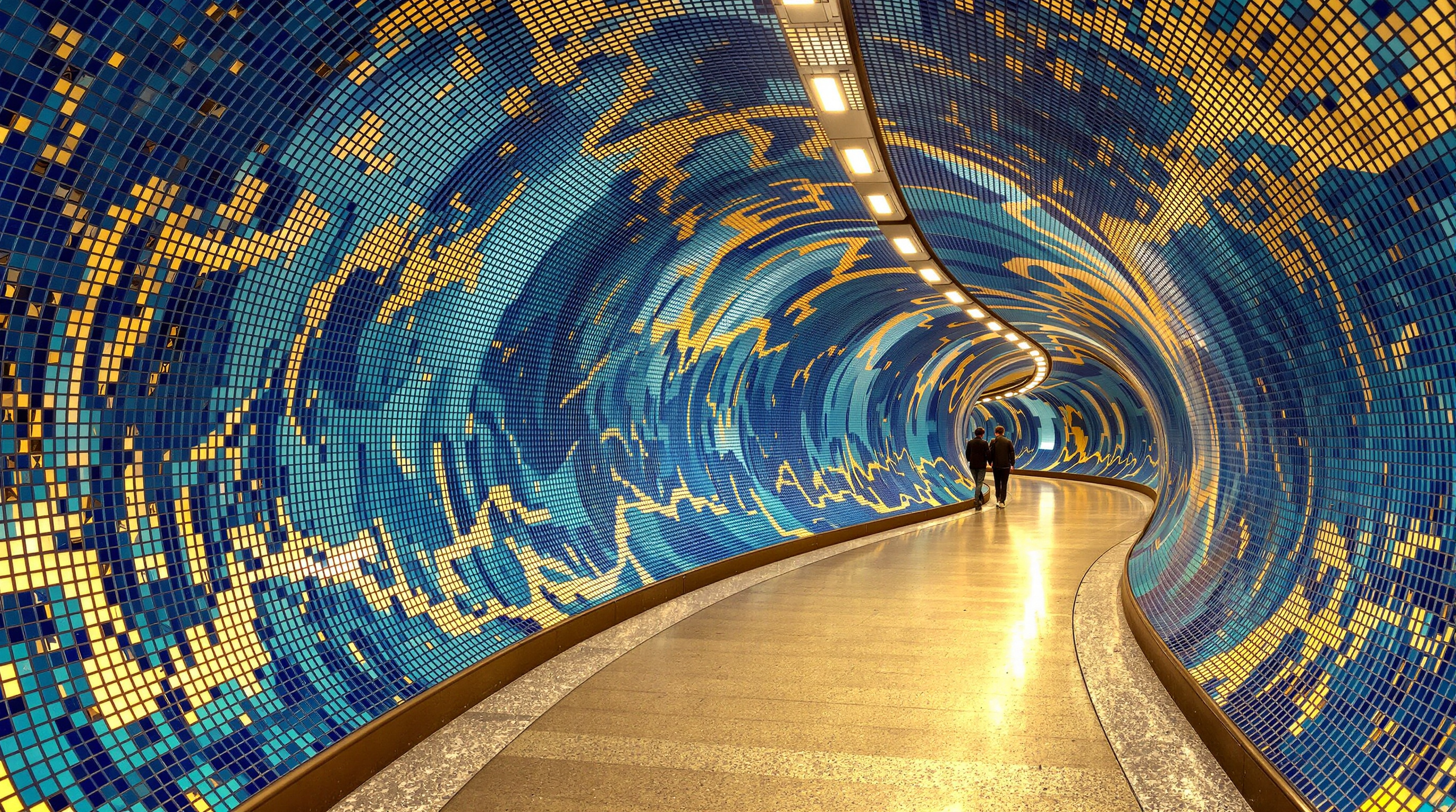 The platform level of Szent Gellért tér station, its curved connecting tunnel sheathed in a swirling psychedelic mosaic of thousands of small shimmering tiles in blues and golds that ripple like sunlight on water, echoing the Zsolnay ceramics of the nearby Gellért Baths