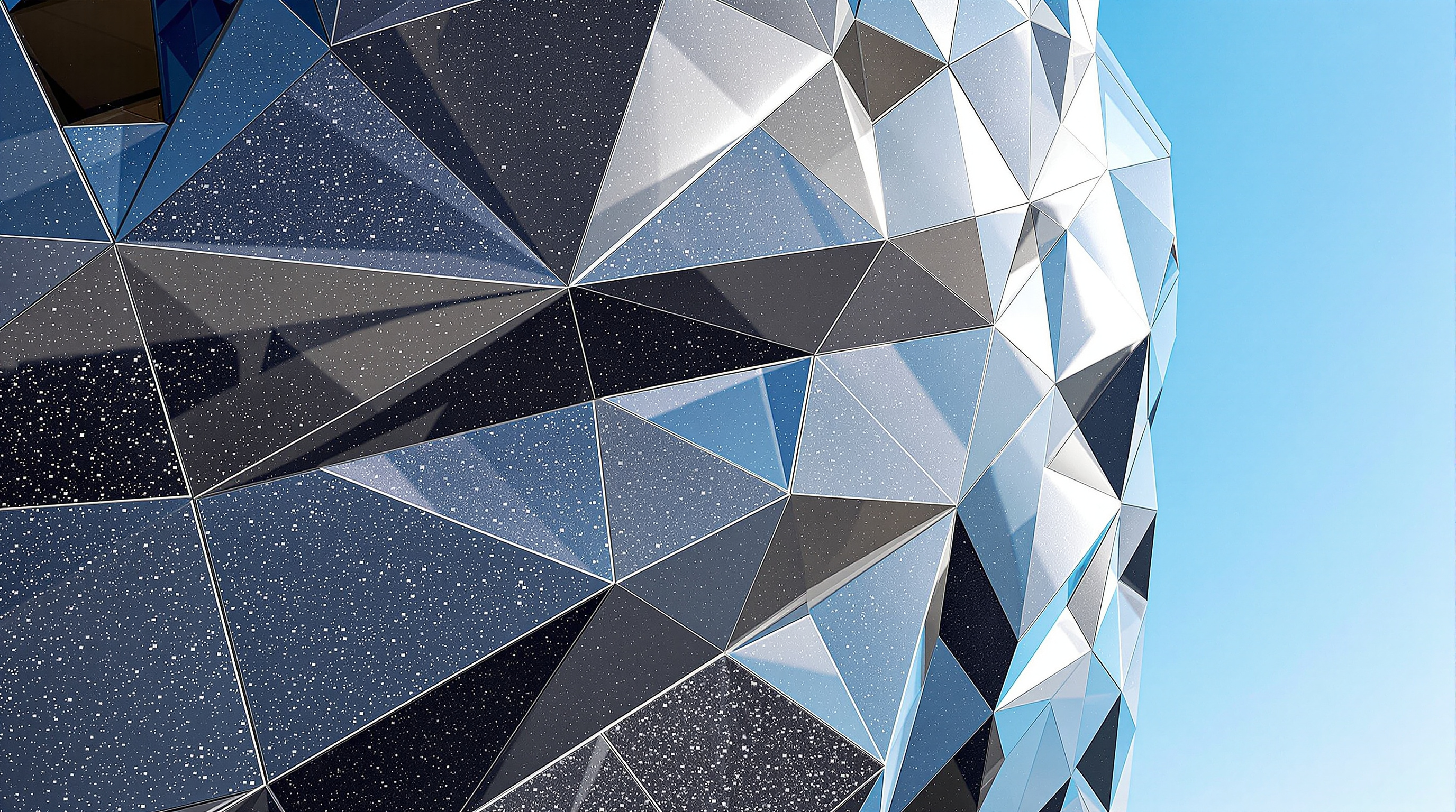 Close view of the Guangzhou Opera House facade showing the faceted skin of flat granite panels and triangular glass sections meeting at sharp angles, the thin joint lines between individual stone panels tracing the curved boulder form against a bright sky