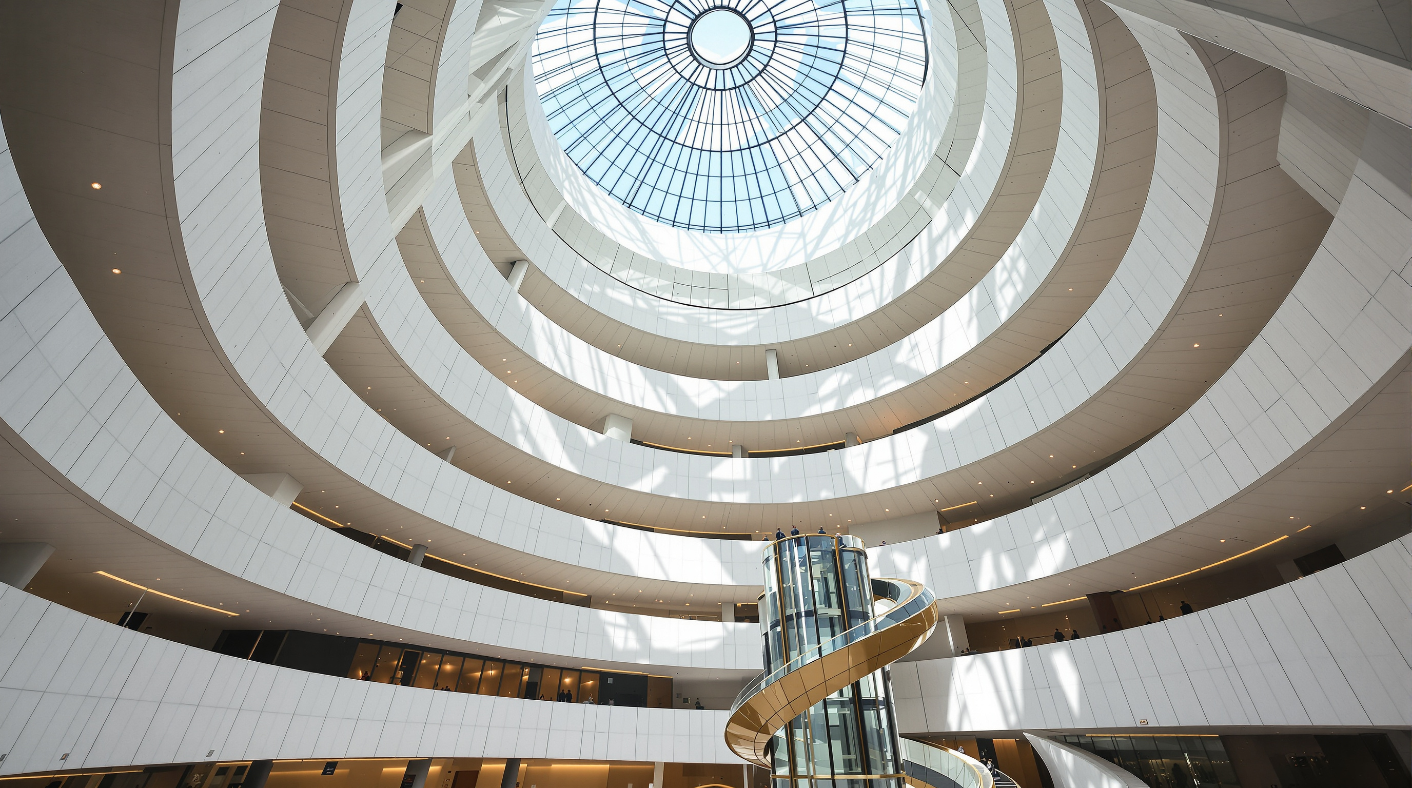 Inside the soaring central atrium of the Guggenheim Bilbao, curving white plaster walls and glass sweeping up nearly fifty metres to a skylight, with sculptural balconies and glass elevators threading through the light-filled void