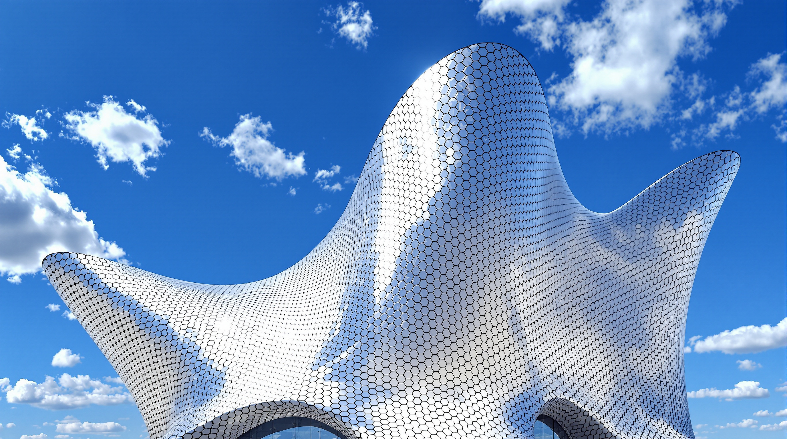 The sculptural silver mass of Museo Soumaya seen against a blue sky, its narrow waisted base flaring outward to a broad overhanging crown, the mirrored hexagonal skin rippling with reflections of clouds and the surrounding plaza