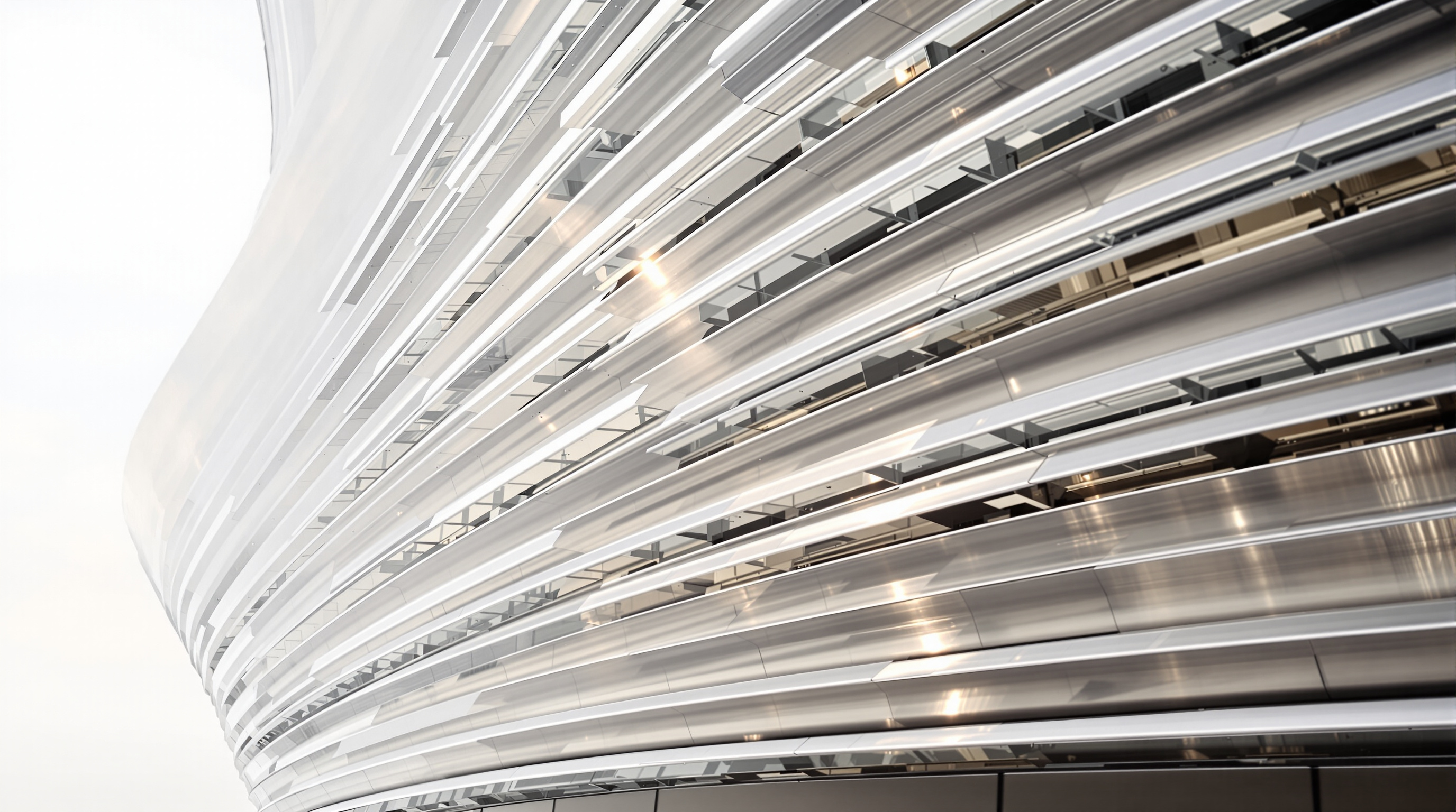 Close-up of the Ordos Museum's polished metal louver facade, horizontal bands of brushed and mirror-finished panels curving around the double-curved form and reflecting the pale desert sky