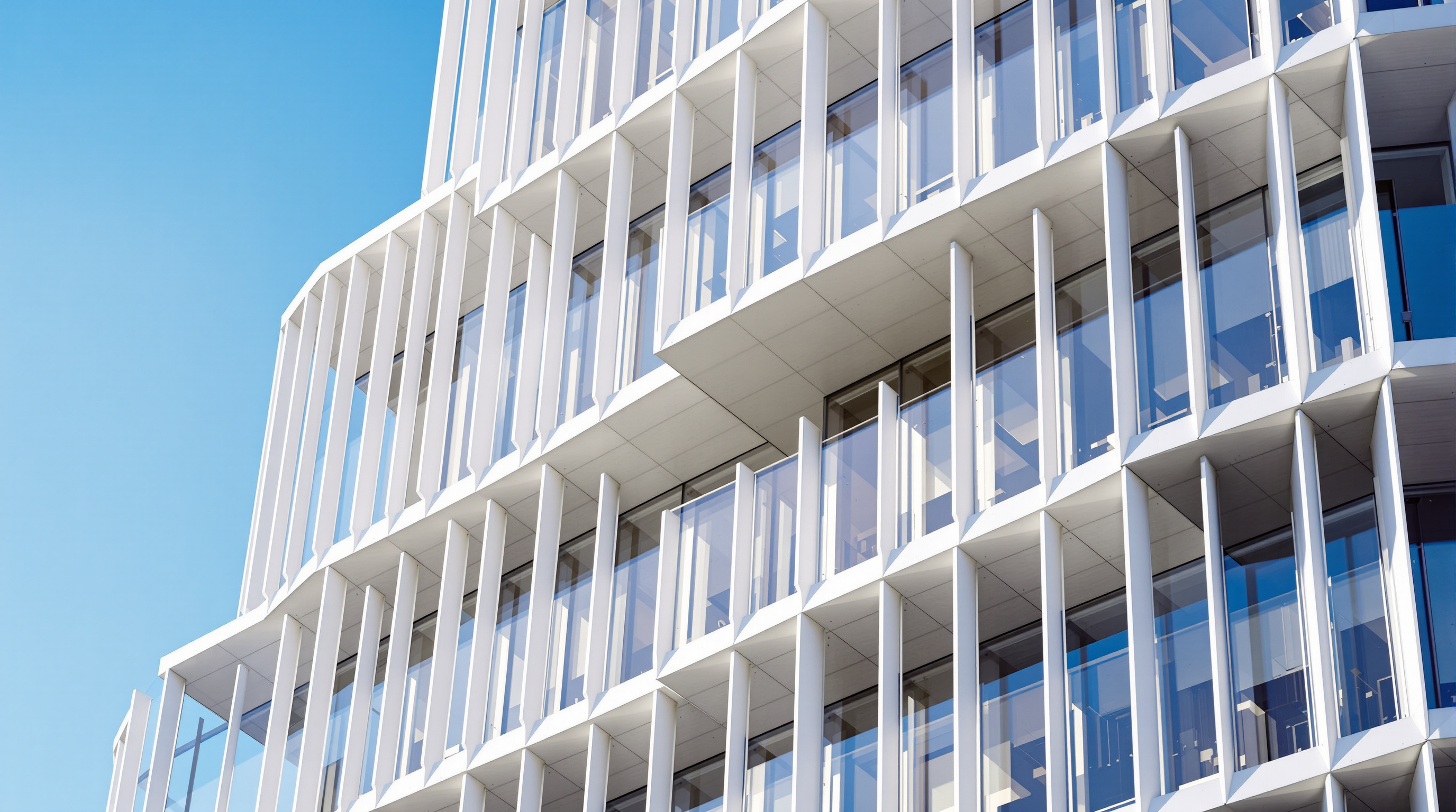 Detail of Quay Quarter Tower's stepped facade against a blue Sydney sky, where two of the five stacked volumes meet and shift, the pale vertical mullions and angled glass reading as distinct blocks rotated one above the other