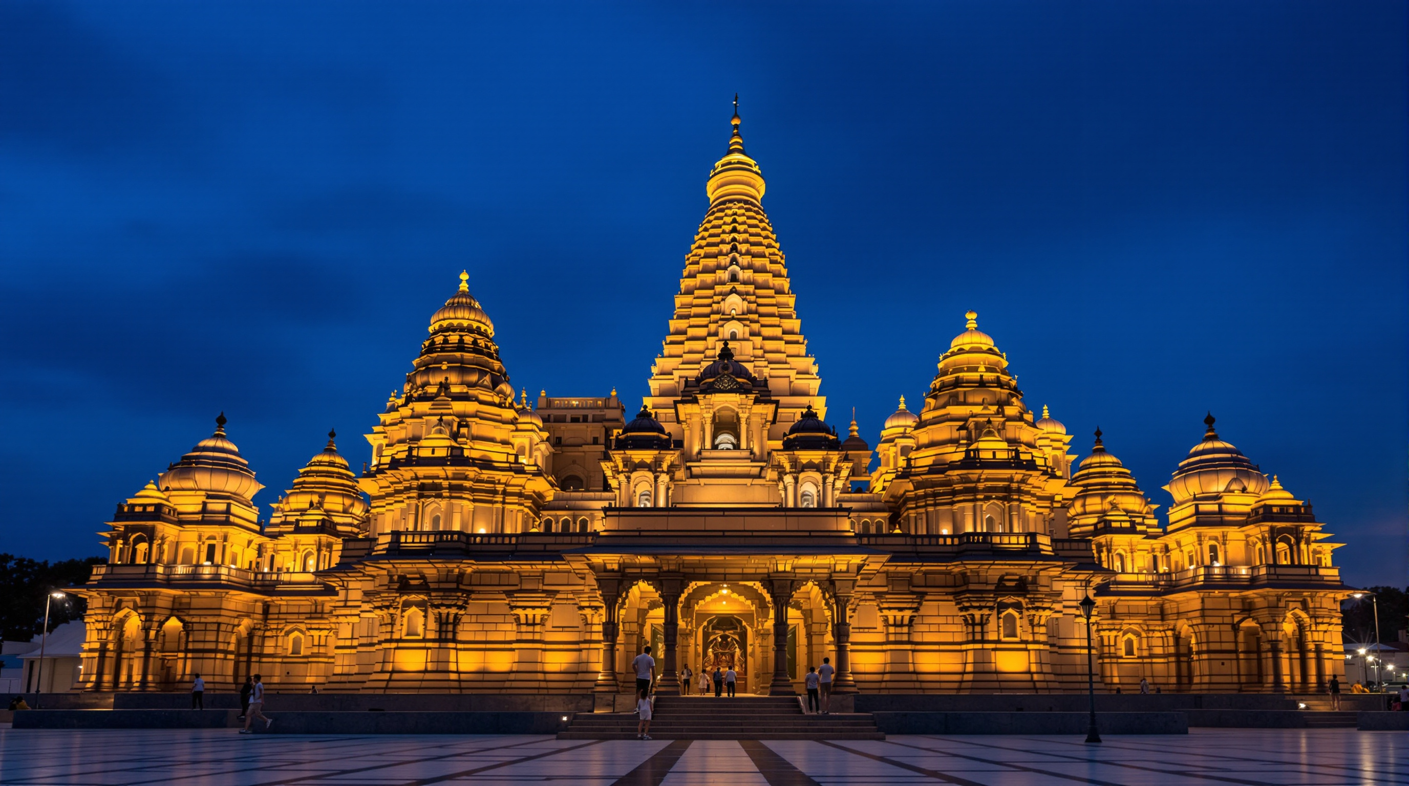 The Ram Mandir seen at dusk with its multiple sandstone shikharas illuminated against a deep blue sky, the tiered spires stepping up toward the tallest central tower above the sanctum