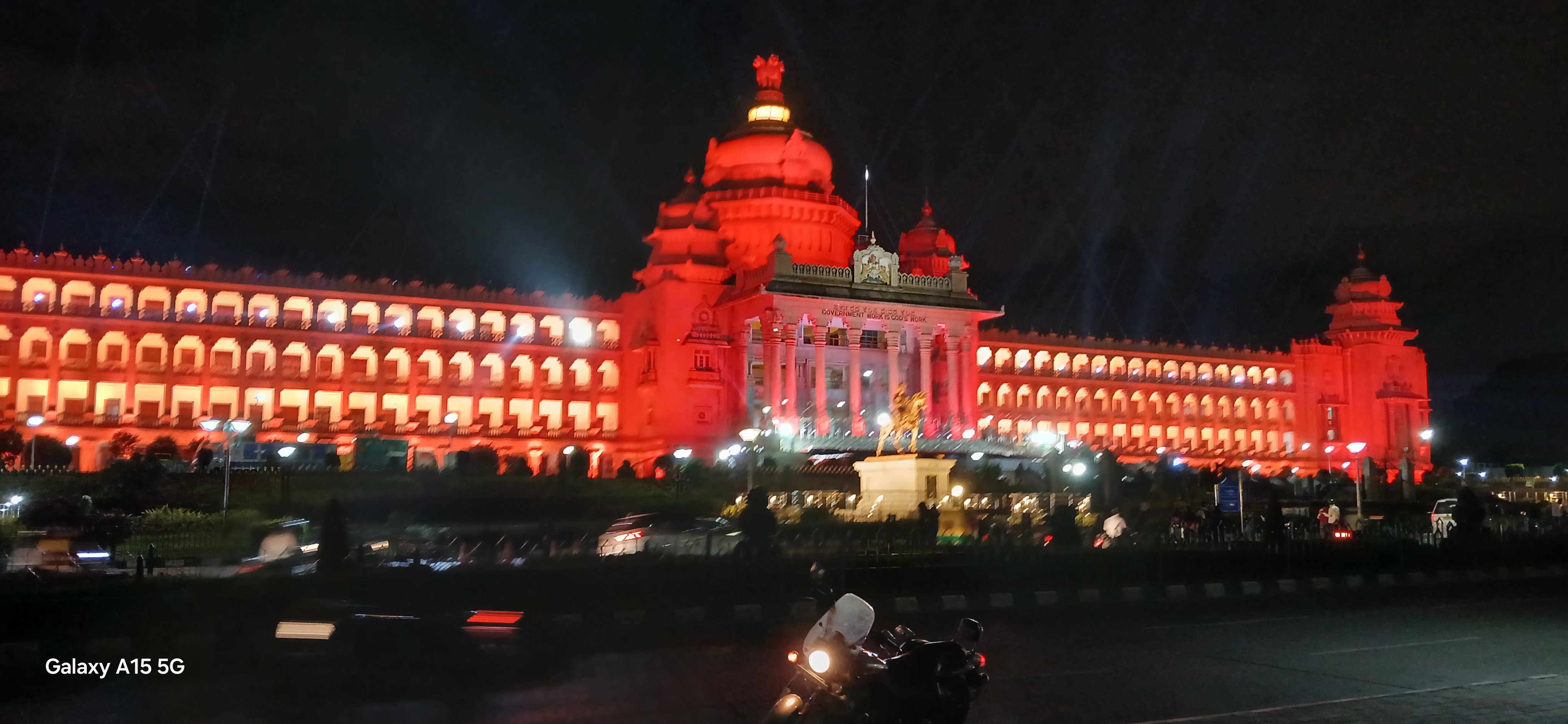 The illuminated granite facade and central dome of the Vidhana Soudha photographed at night.