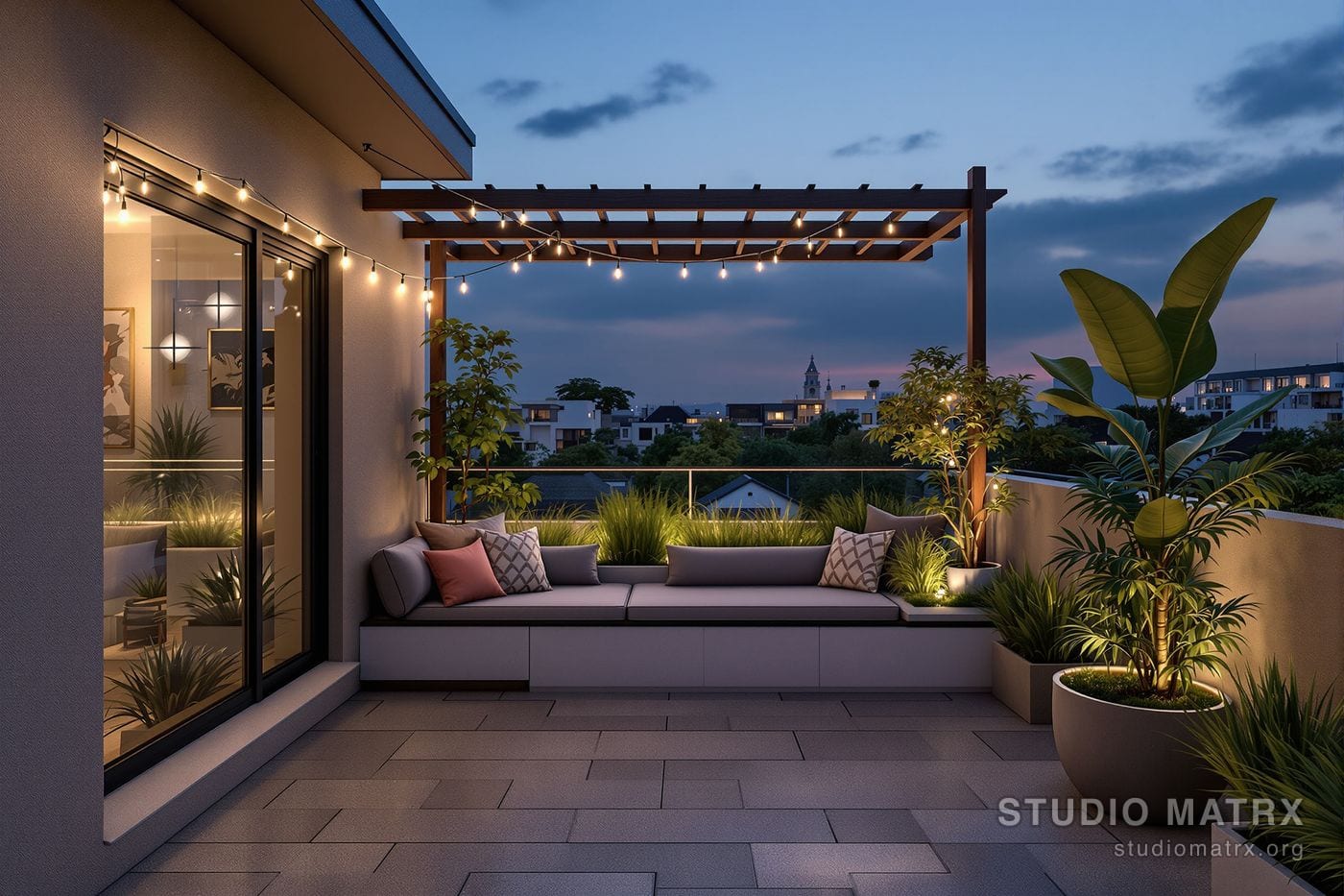 A compact private rooftop terrace on a small modern Indian home at dusk - a slim timber pergola overhead, a built-in bench, planters of ornamental grasses and a frangipani, warm string lighting, a glass parapet, with neighbouring rooftops beyond.