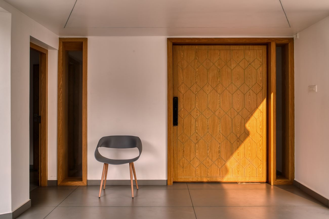 The entry foyer of Skew House with a tall teak door and warm light