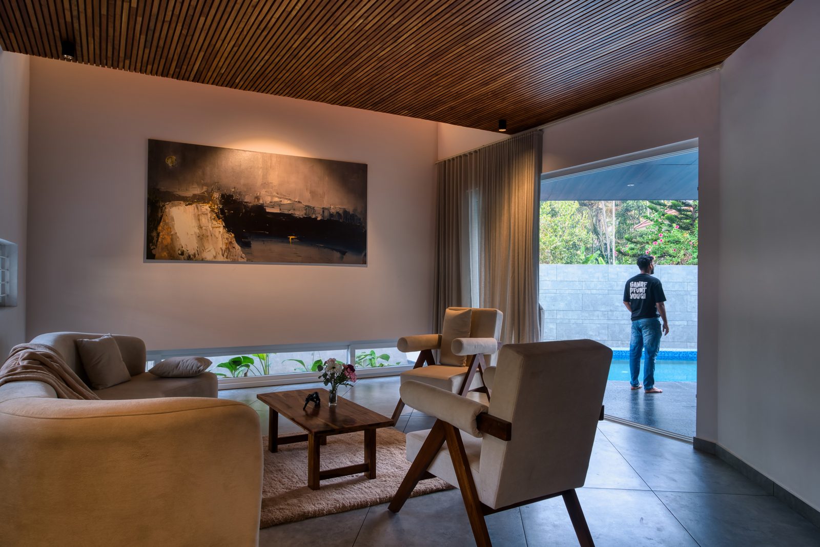 Skew House living room with a slatted timber ceiling and a glazed wall opening to the pool