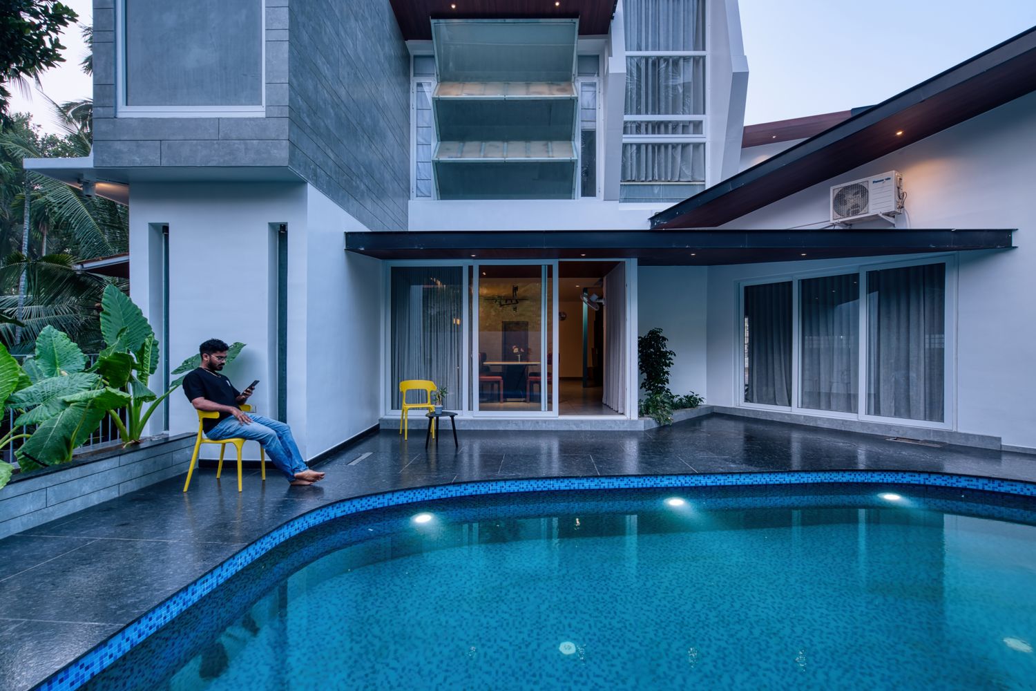 The pool courtyard of Skew House framed by angular glazed volumes and planting