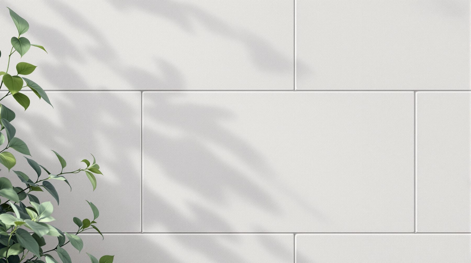 A clean wall of pale-grey precast concrete blocks with soft leaf shadows