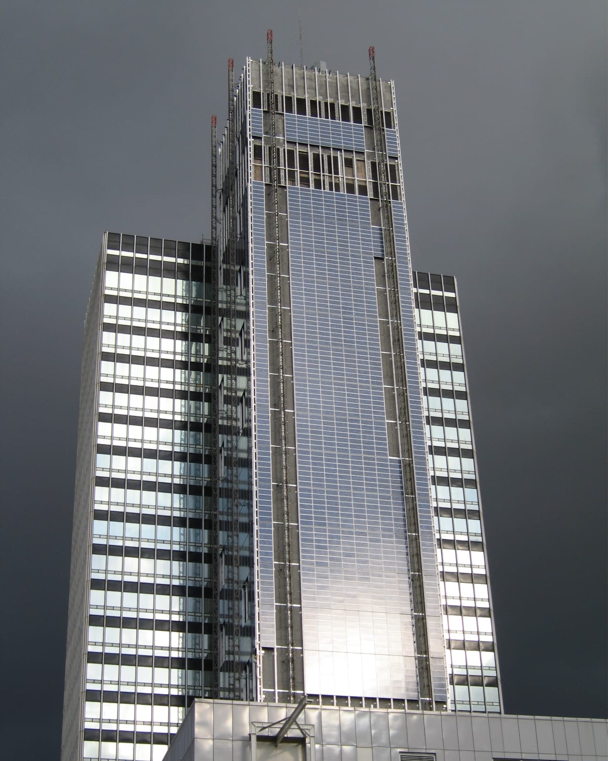 The CIS Tower in Manchester being re-clad in photovoltaic tiles, against a dark sky