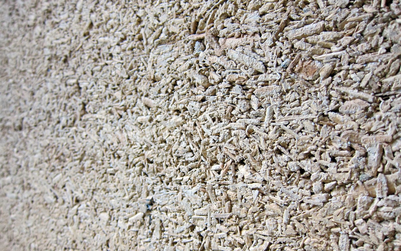 Close-up of a real hempcrete wall showing hemp-hurd particles bound in lime