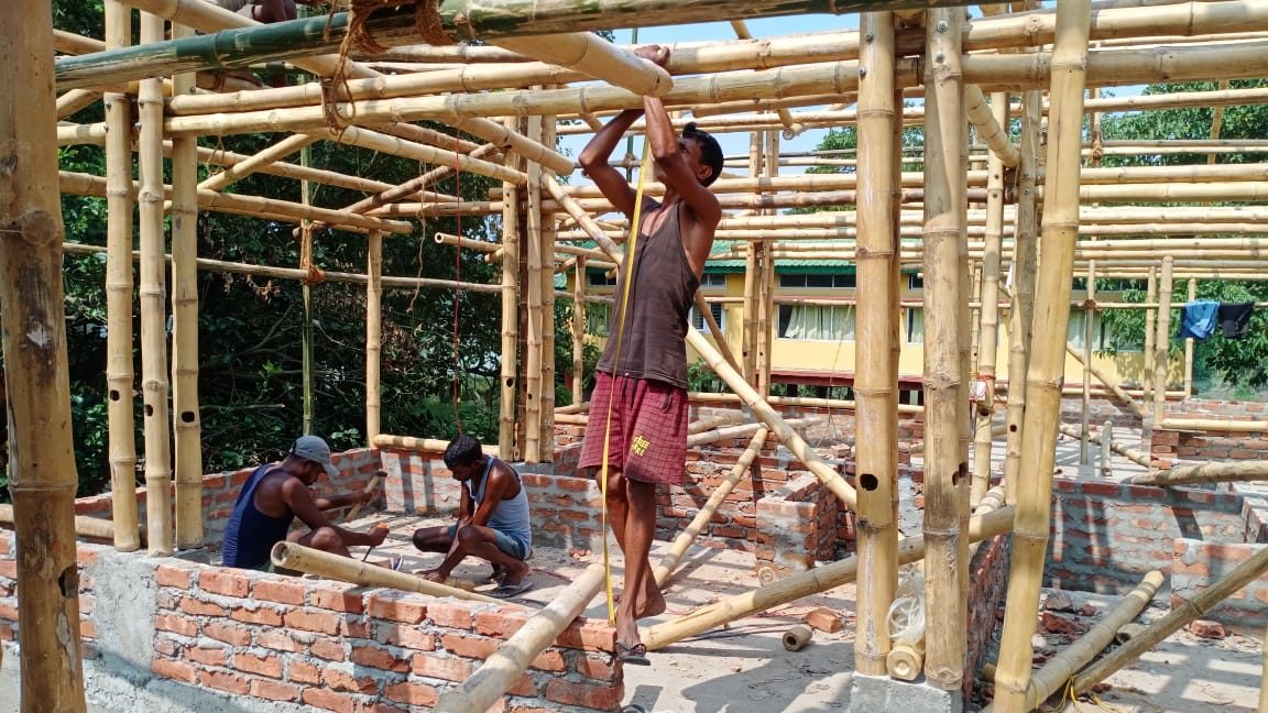 Local workers assembling the bamboo superstructure of the barracks over the masonry base