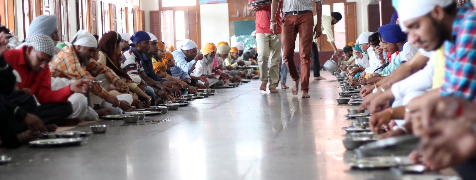 A vast langar dining hall at the Golden Temple with long seated rows stretching the length of the room