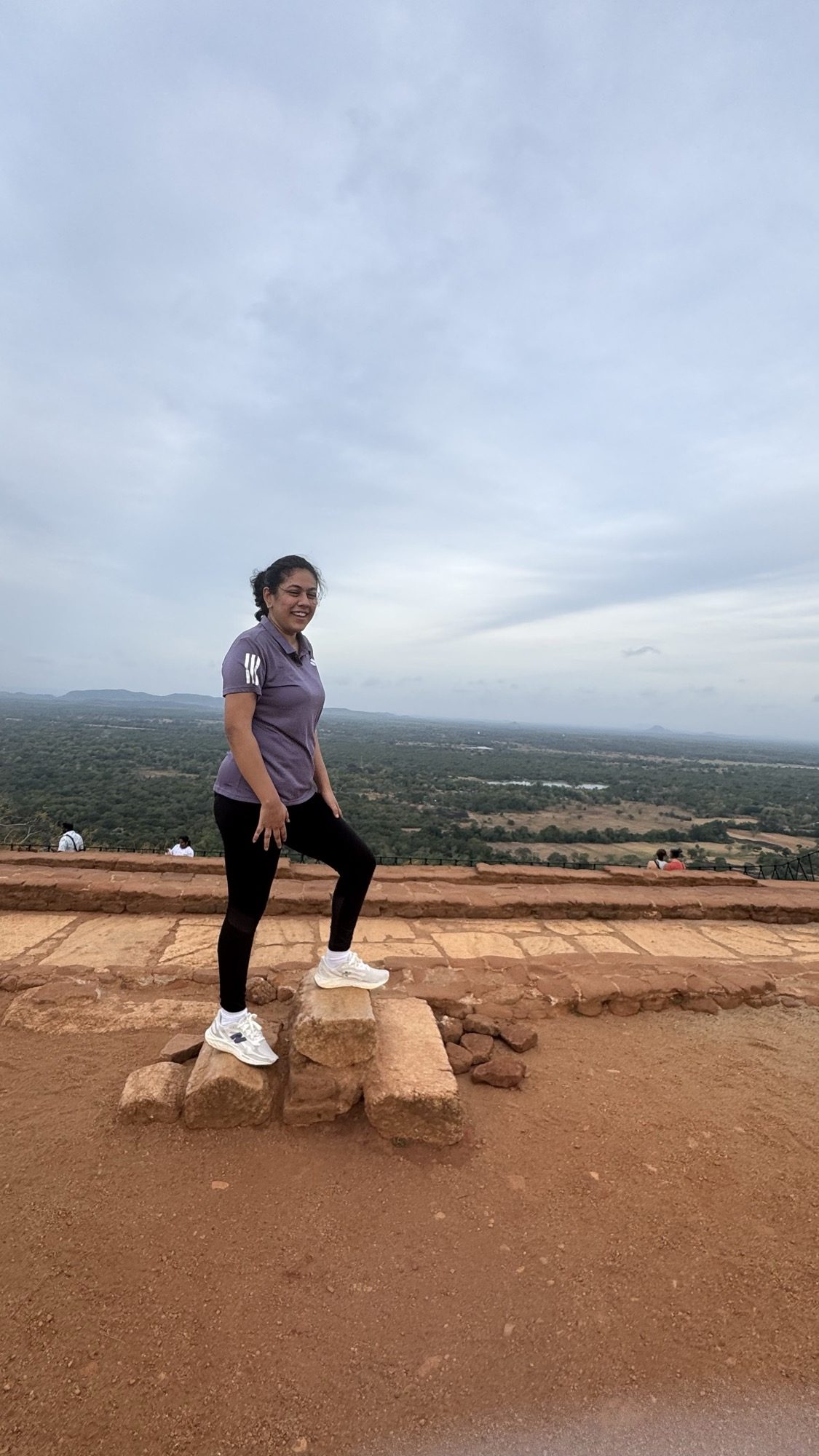 A quiet moment on the summit of Sigiriya, looking out over the enormous green plain under a soft overcast sky