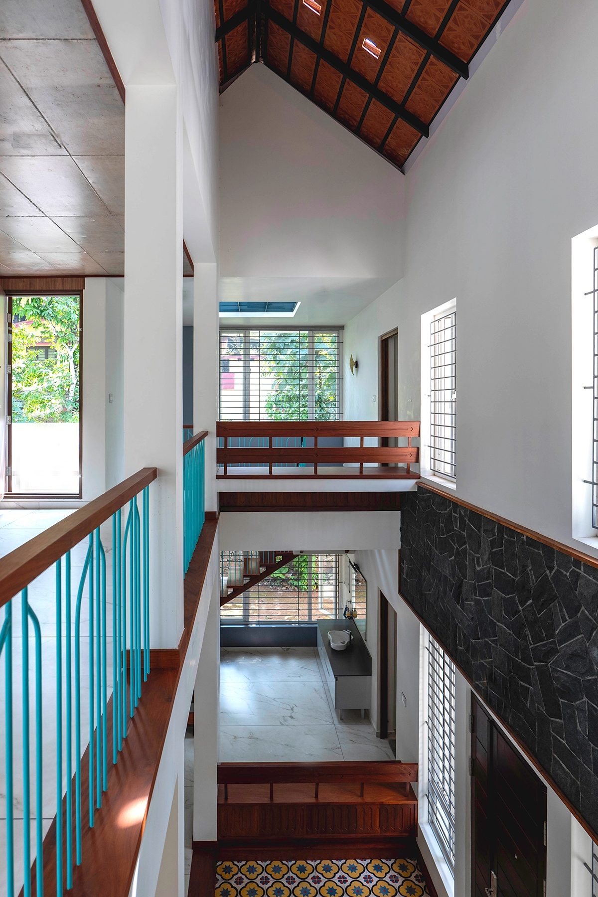 The upper passage with its turquoise balustrade, windows at several heights, the timber roof and a black stone band along the central volume