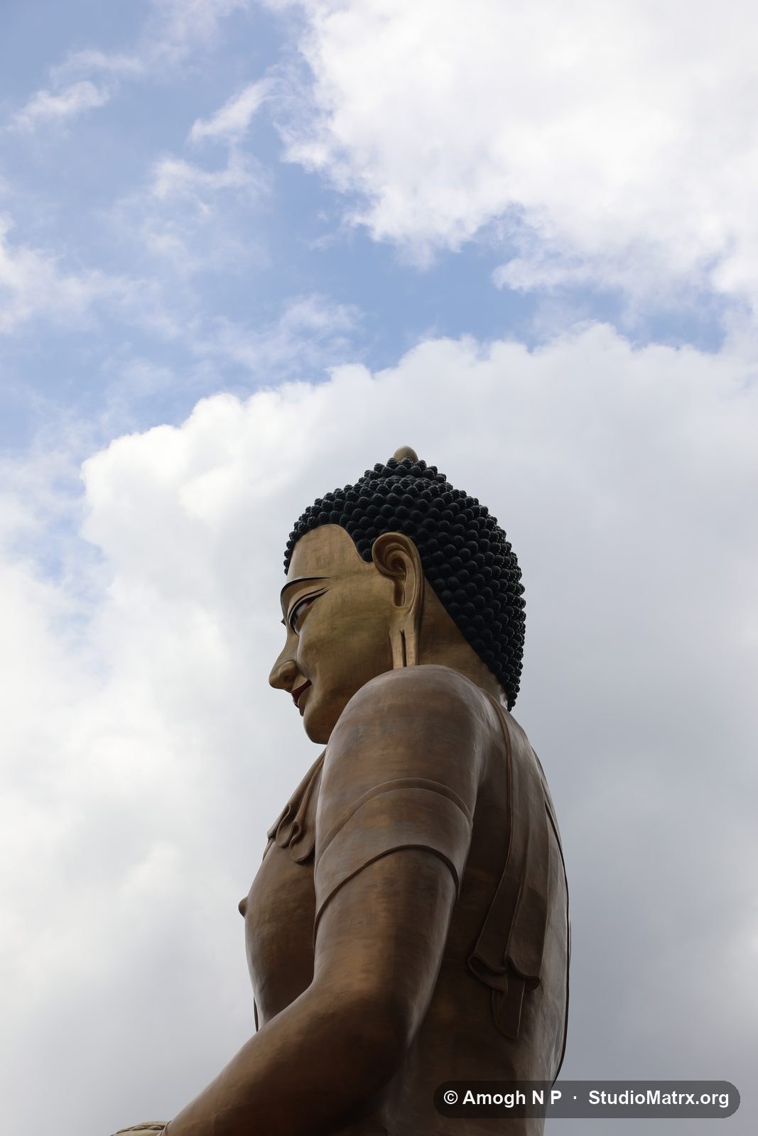 The Buddha Dordenma in profile against white cloud and blue sky