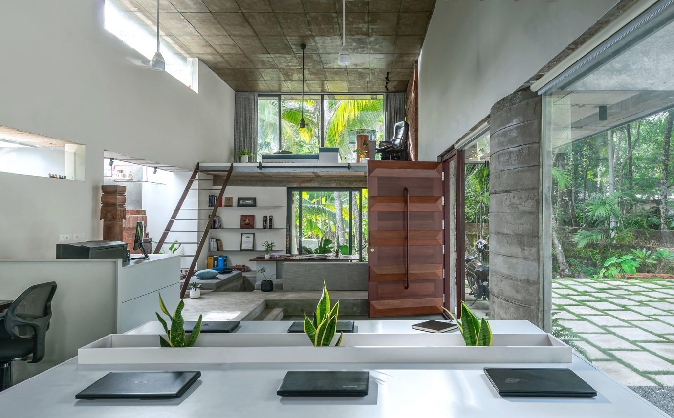 The Violet Office interior — workstations, conversation seating, an upper workspace, a timber door and glazing onto palms