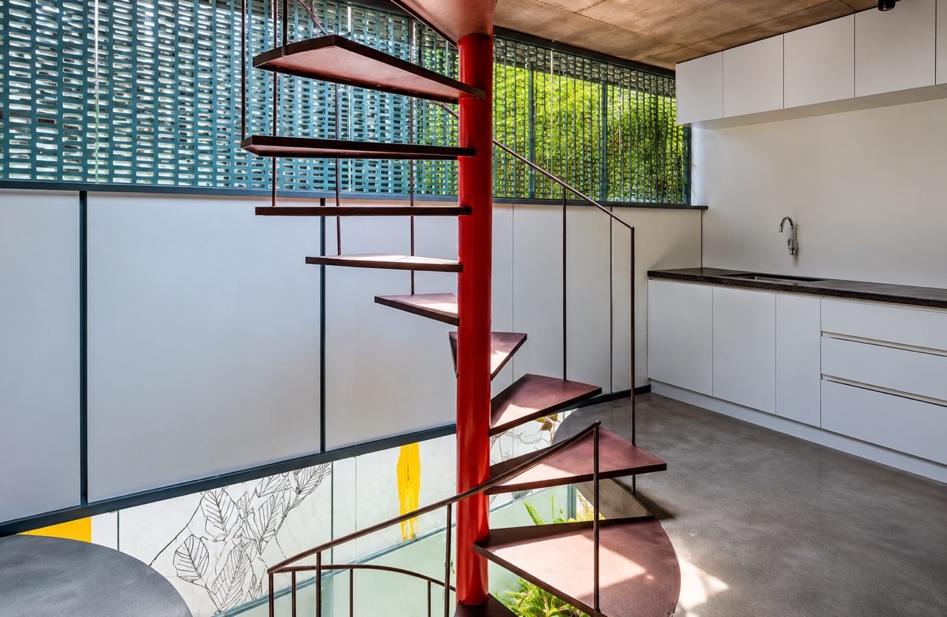 The pantry beside a red spiral stair, with a perforated screen and planting