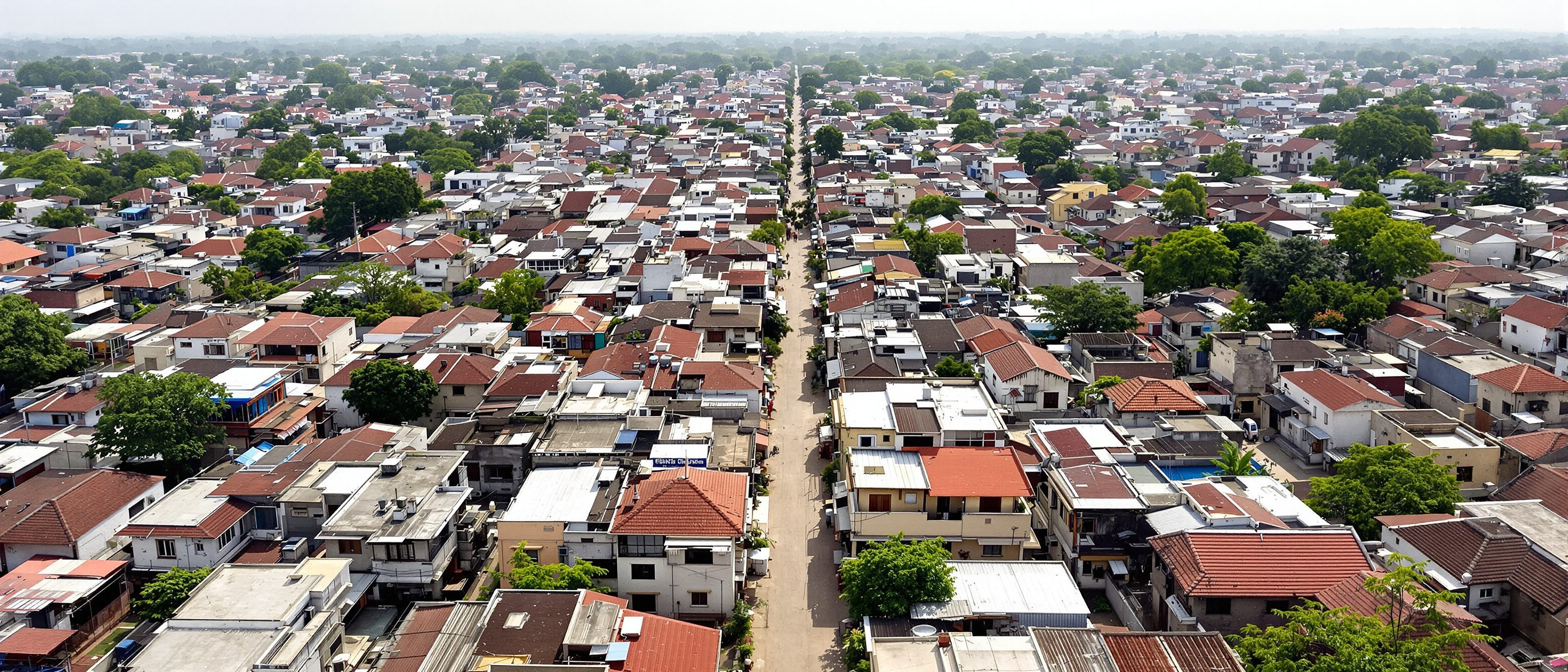 An aerial view of a dense Indian residential neighbourhood of individual plots along an internal road — the urban fabric that development-control rules (FSI, coverage, setbacks) shape plot by plot.