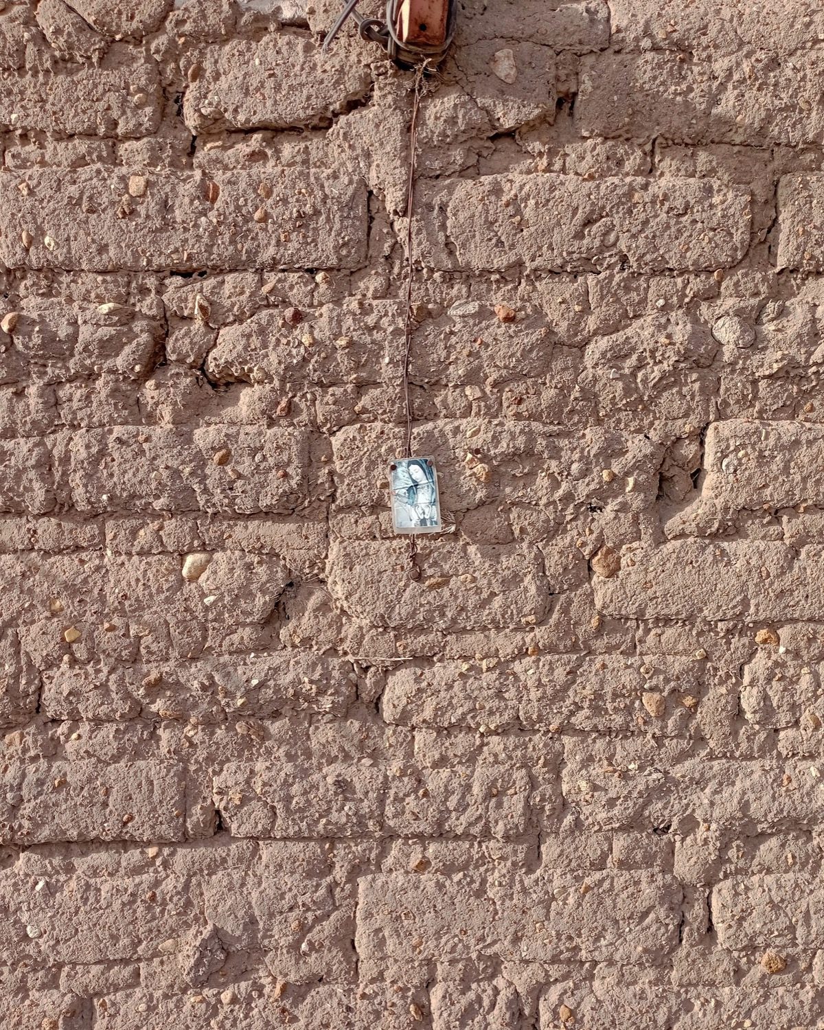 A thick earthen (adobe) wall — high thermal mass delays and damps the daily heat swing.