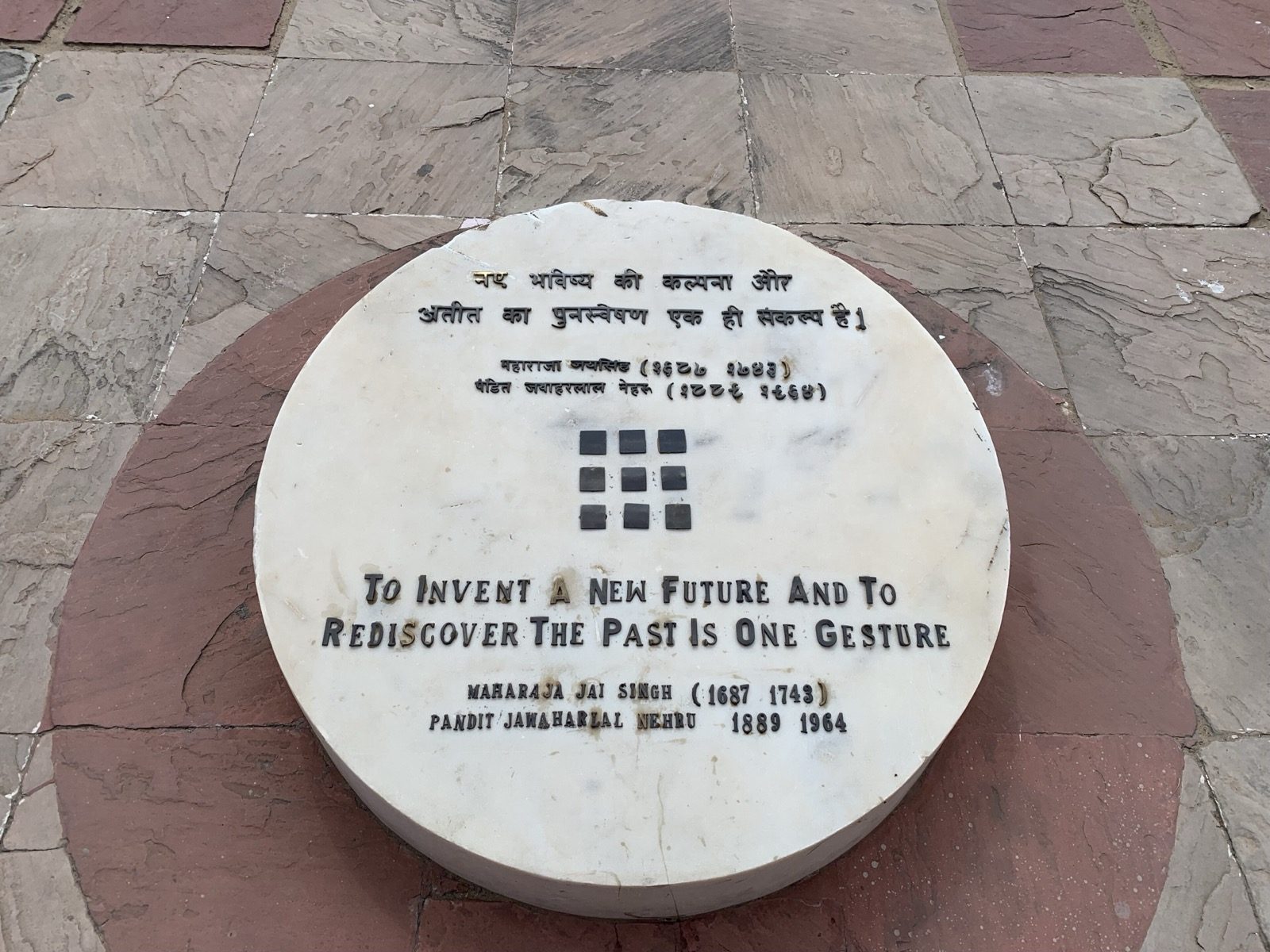 The dedication plaque at Jawahar Kala Kendra, Jaipur (Charles Correa, 1986–92) — Correa's nine-square symbol and the inscription, 'To invent a new future and to rediscover the past is one gesture.'