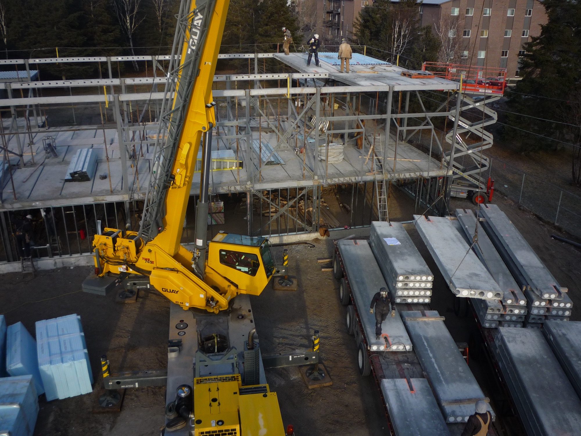 A steel beam-and-column frame under construction — I-section beams carry precast floor planks that laterally restrain the compression flange.