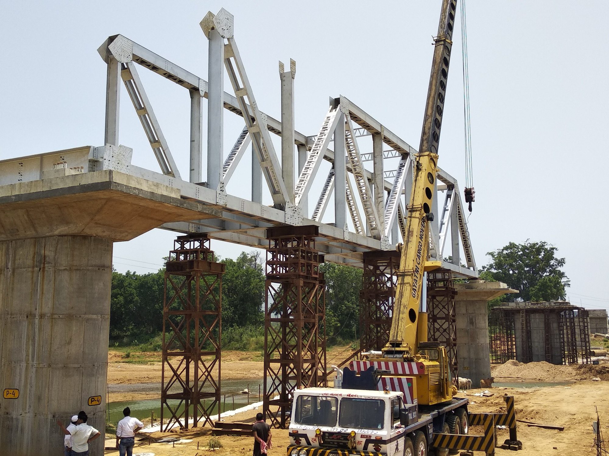 A steel girder-and-truss bridge being erected — built-up steel sections lifted into place, the raw material of steel design.