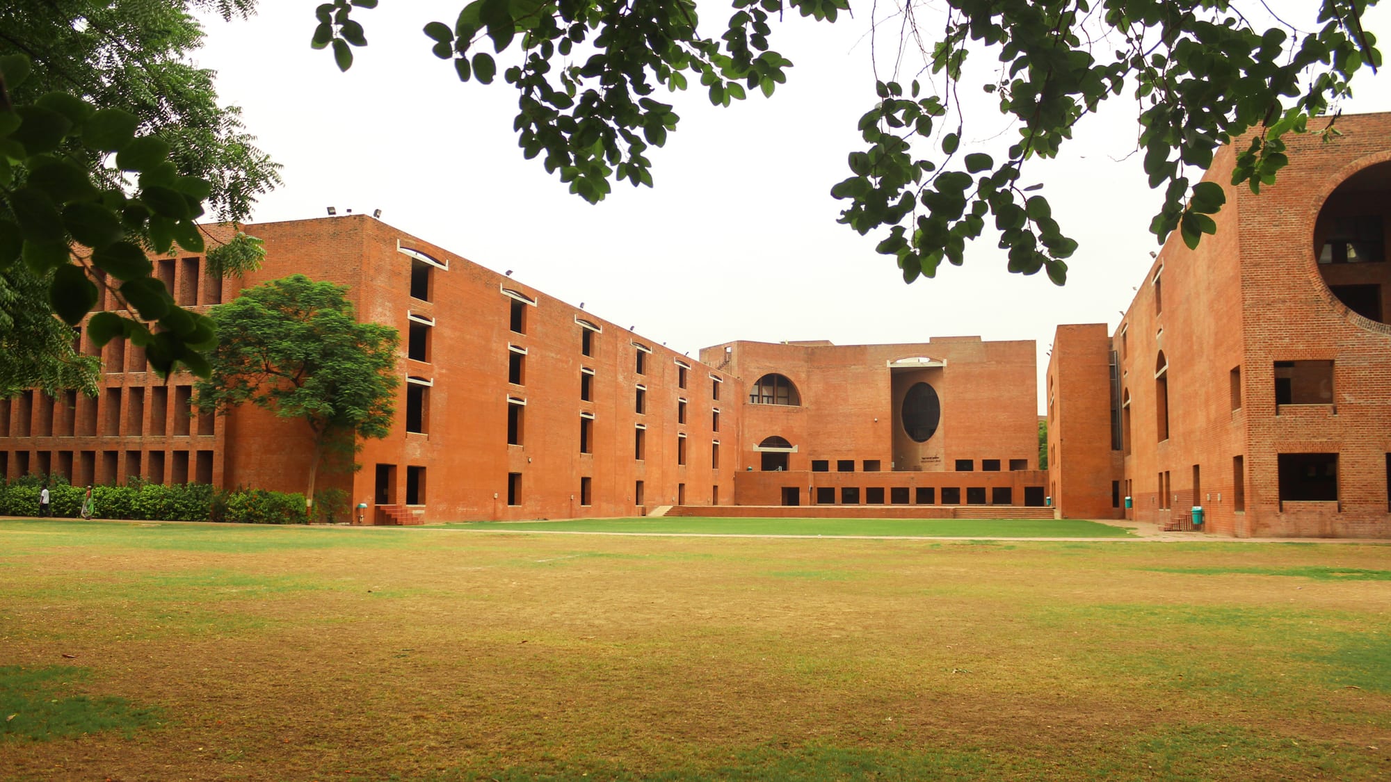 Louis Kahn's Indian Institute of Management, Ahmedabad — monumental brick geometries of circles and arches cutting deep shade into massive walls.
