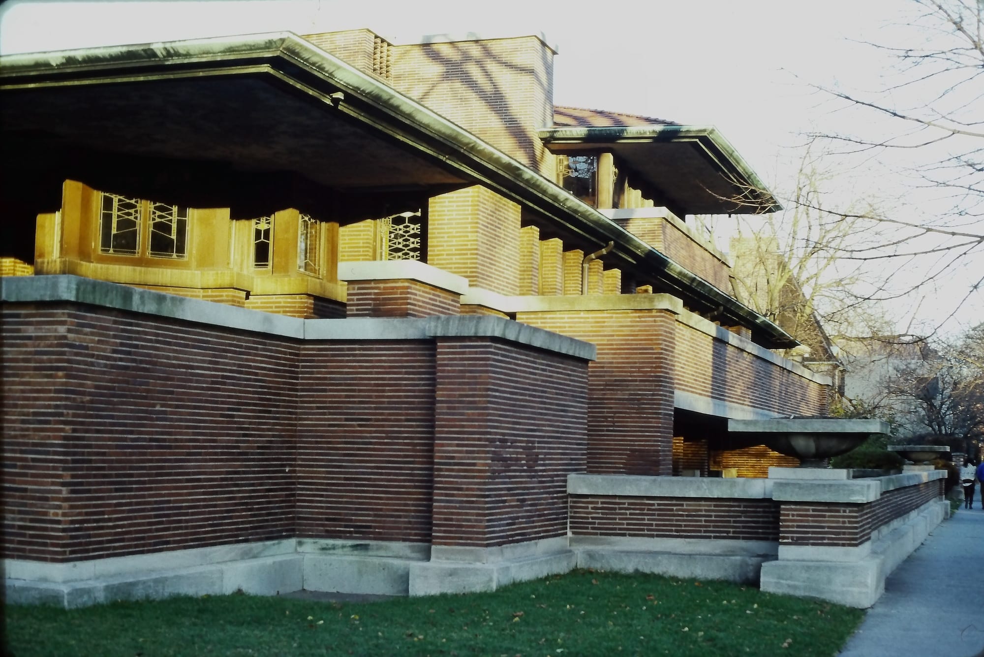 A Frank Lloyd Wright Prairie house — low and emphatically horizontal, with sweeping eaves and bands of windows; open 'organic' space, the doorstep of the modern.
