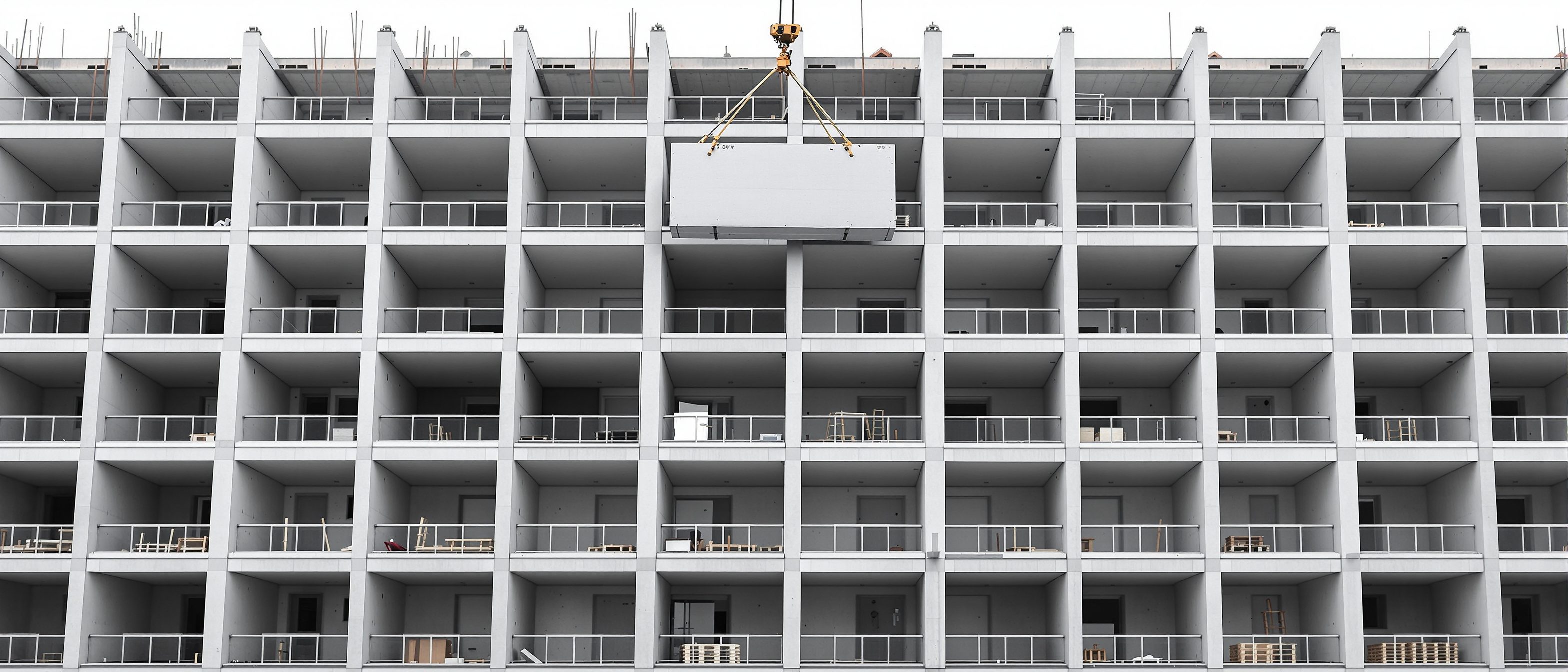 A precast concrete apartment building under assembly showing a clear repeating modular grid of identical wall panels and floor slabs being craned into place, the modular discipline made visible, no readable text.