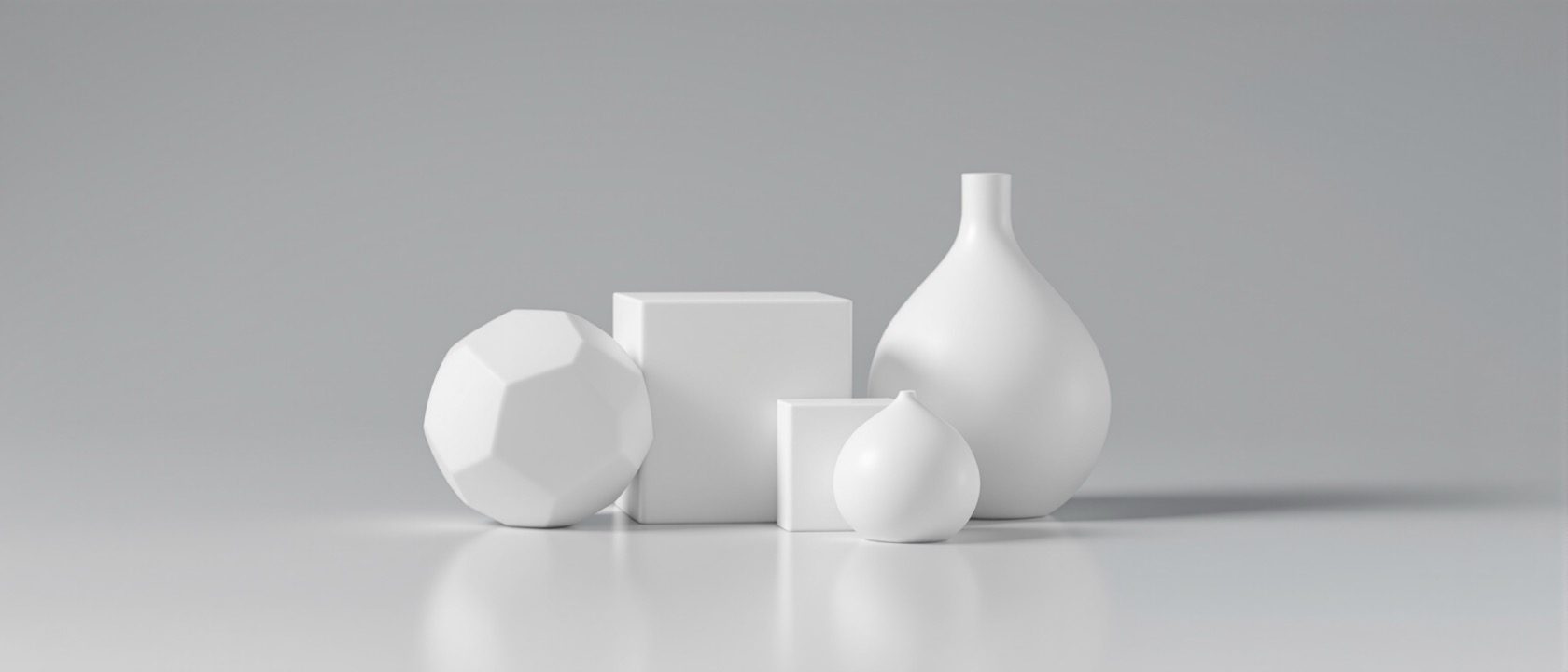 A set of clean white 3D-printed geometric primitives — a faceted sphere, a cube and a smooth curved form — arranged on a matte grey surface in soft studio light