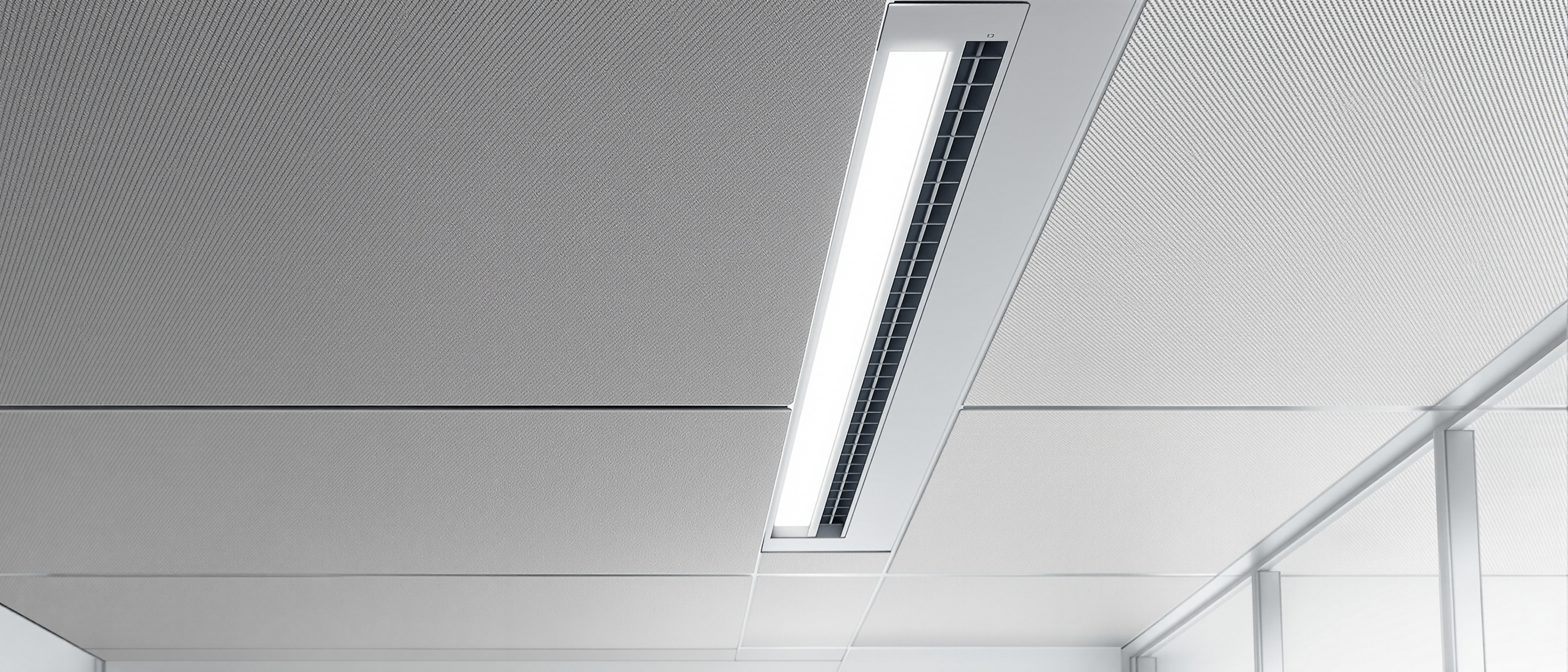 A calm interior ceiling showing coordinated services — a slim linear light, an air-conditioning grille and an acoustic panel set neatly together, in soft daylight, no text
