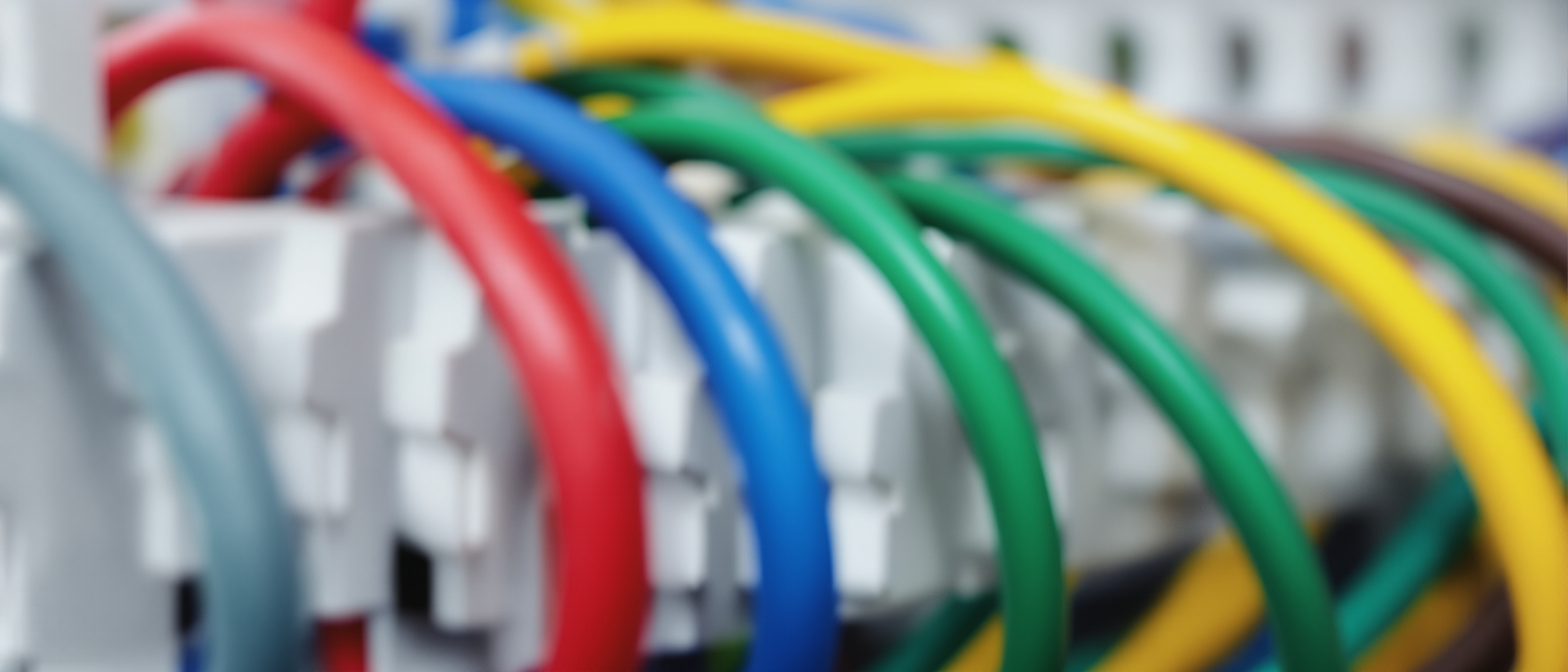 An open electrical distribution board with a neat row of circuit breakers and colour-coded wiring, clean and technical, no legible text