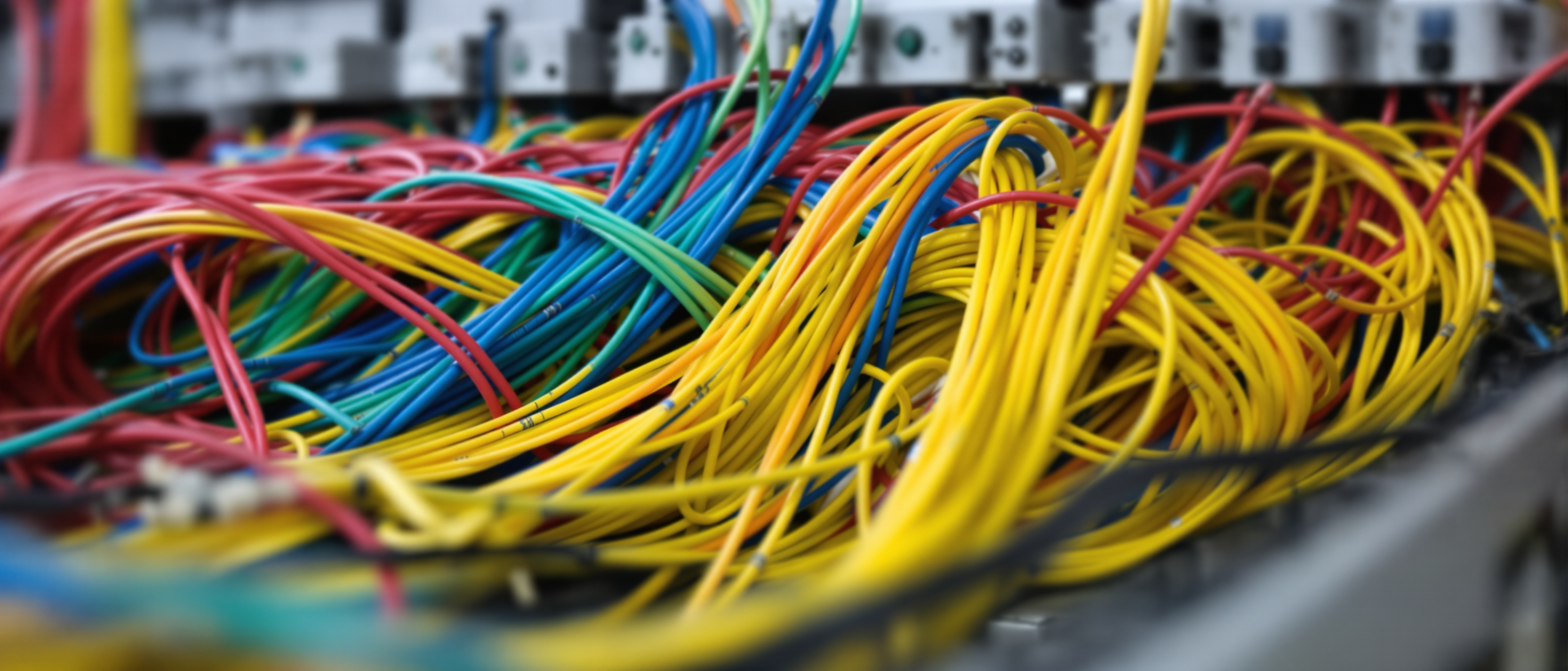 A tidy building-services control room wall of neat cabling and coordinated equipment (no screens), clean and technical, no text