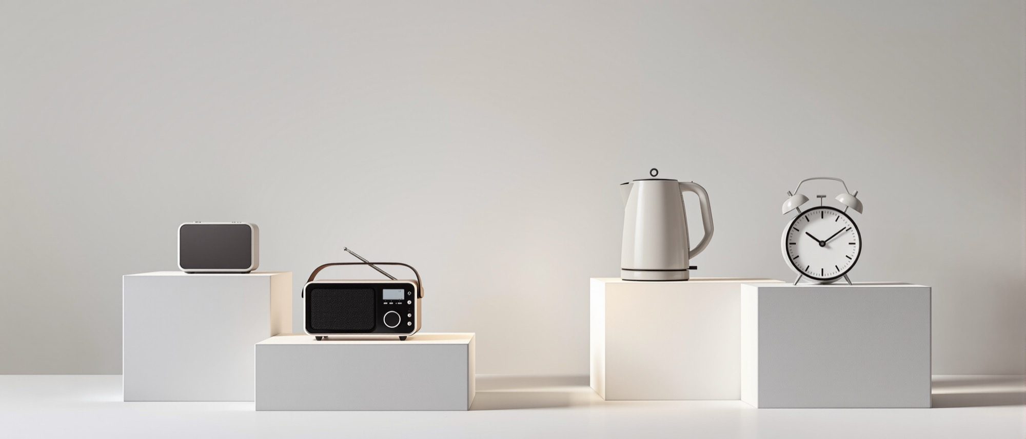 A studio display of well-designed minimalist products — a radio, a speaker, a kettle, a clock — function, use and form resolved into objects.