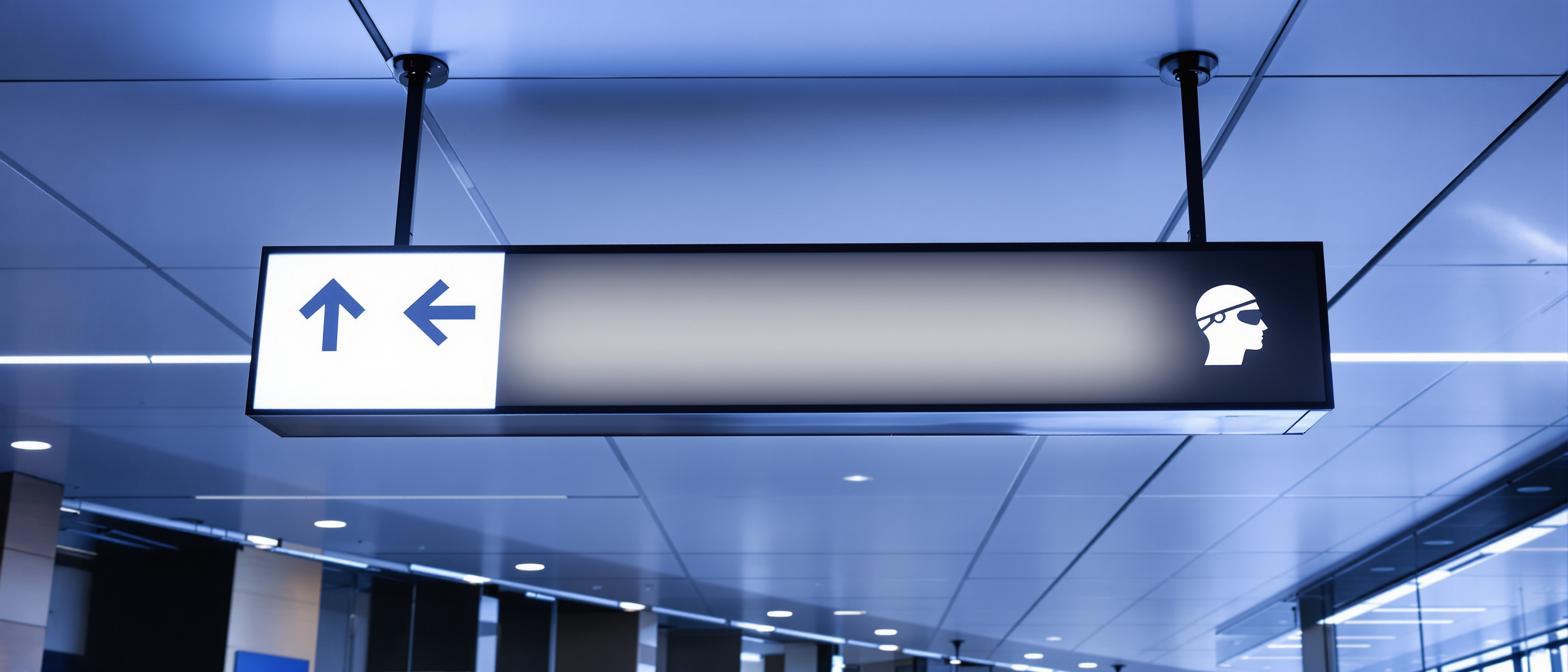 A clean overhead directional signage panel with a few blank spaces for arrows and destinations against a bright ceiling, minimal and graphic, no legible text