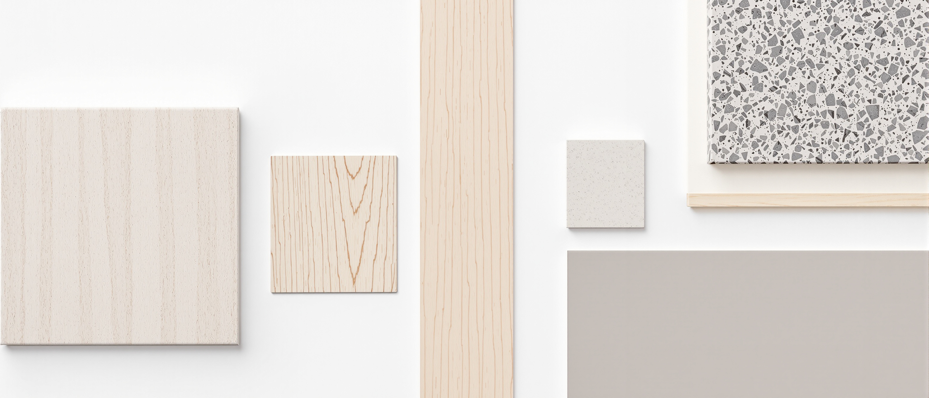 A neat flat-lay of interior material and finish samples — a ceramic tile, a timber veneer strip, a laminate chip, a piece of natural stone and a paint swatch — in a tidy row on white, even daylight, no text